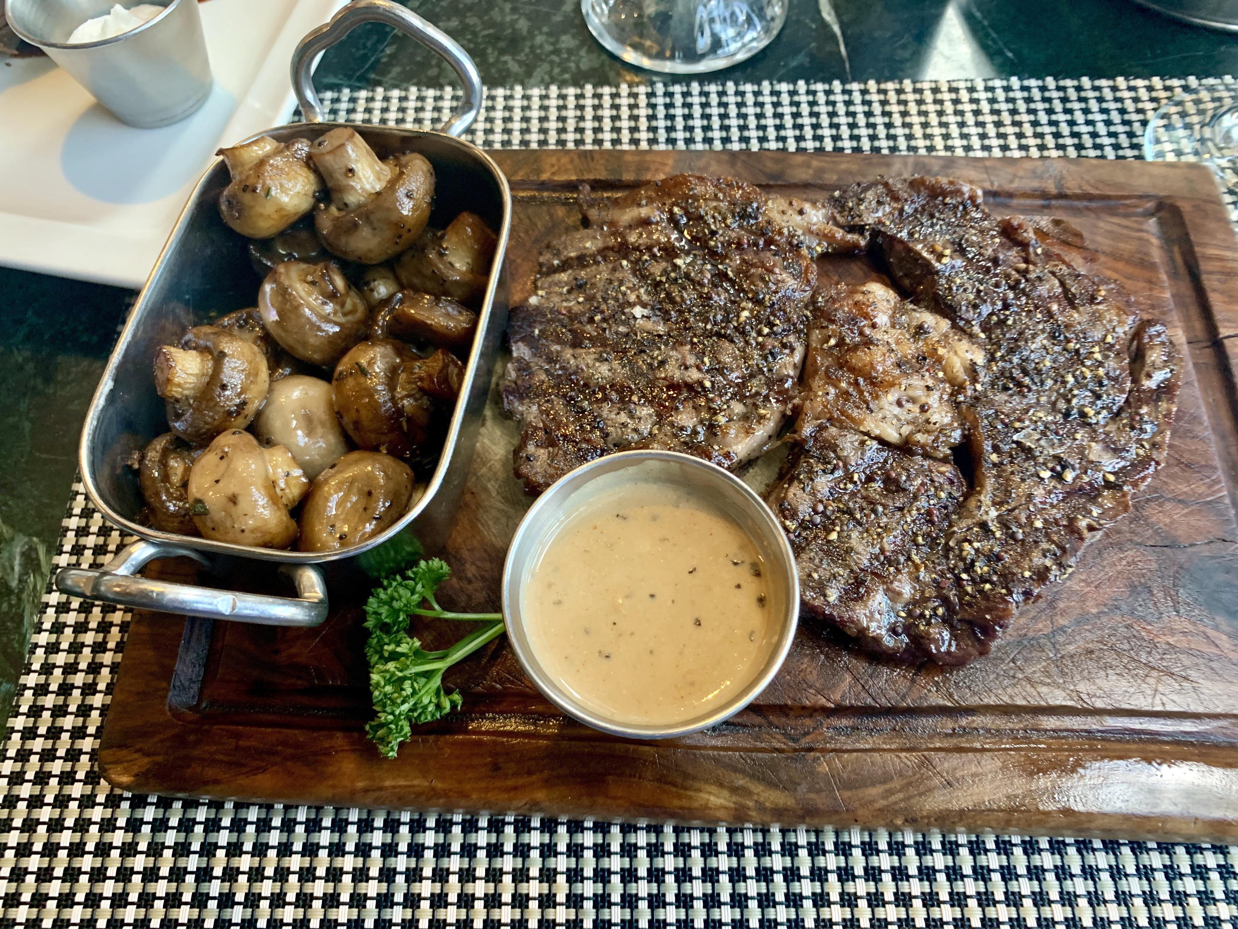 Ribeye wagyu steak with black pepper sauce and sautéed mushrooms. r