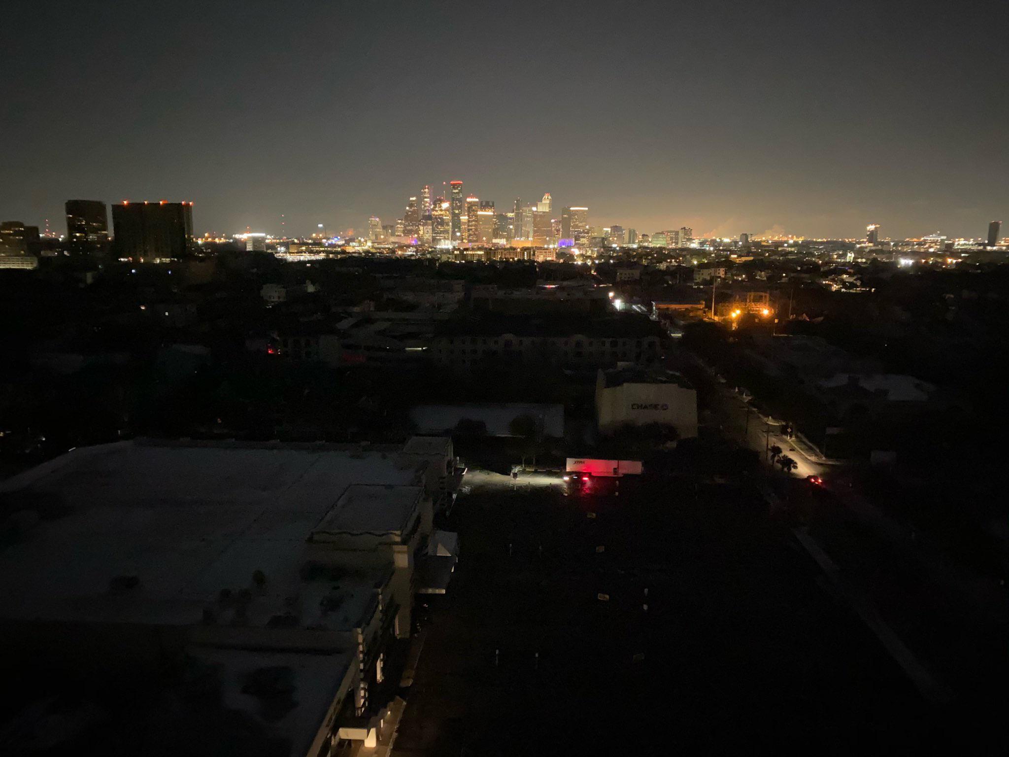 Downtown Houston lit up like the 4th of July while surrounding homes