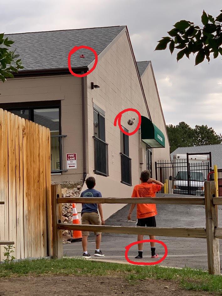 Kid throws flip flop on roof of building. Another kid tries to get it