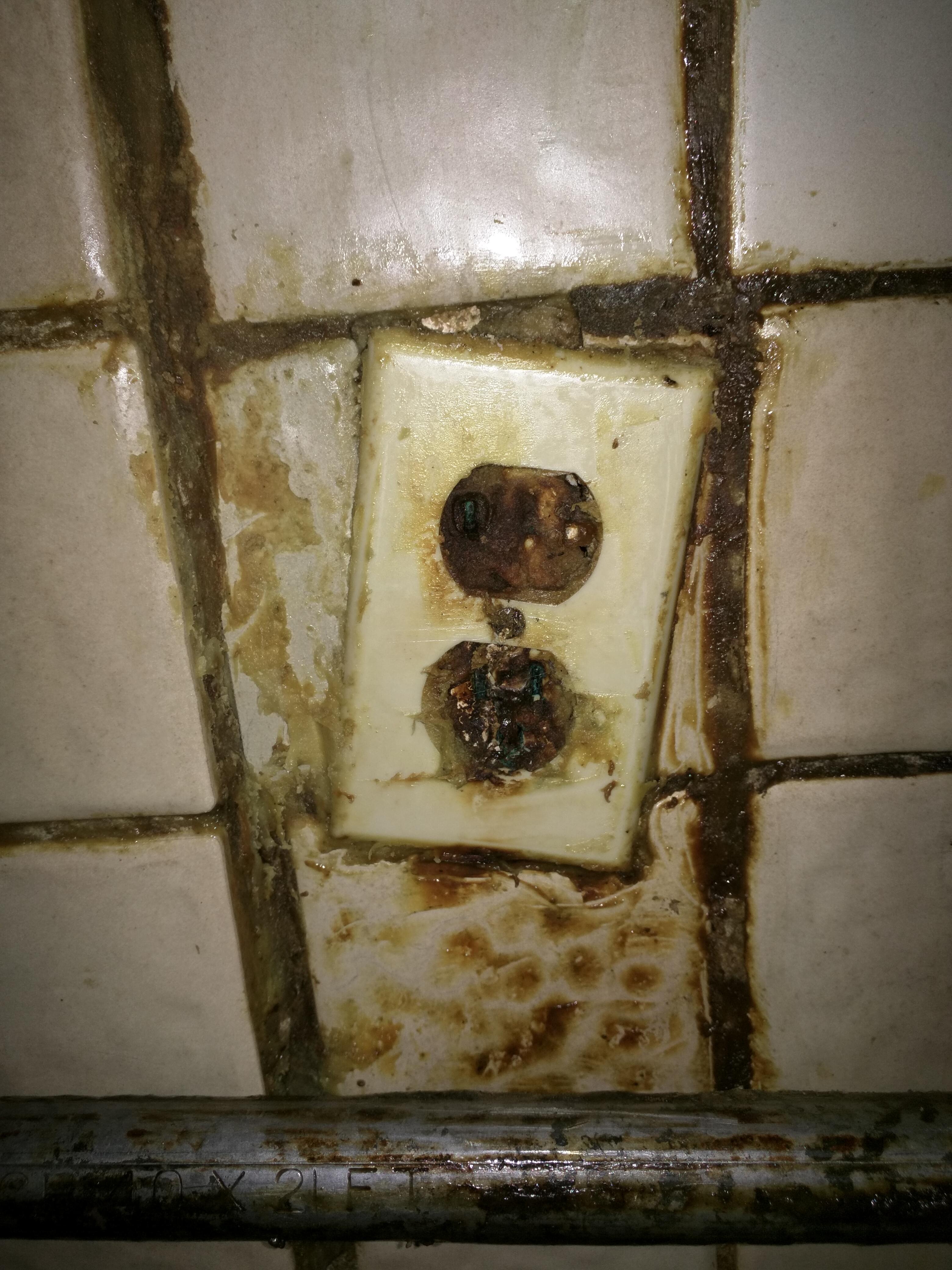 An outlet behind a commercial kitchen stove that probably hasn't seen