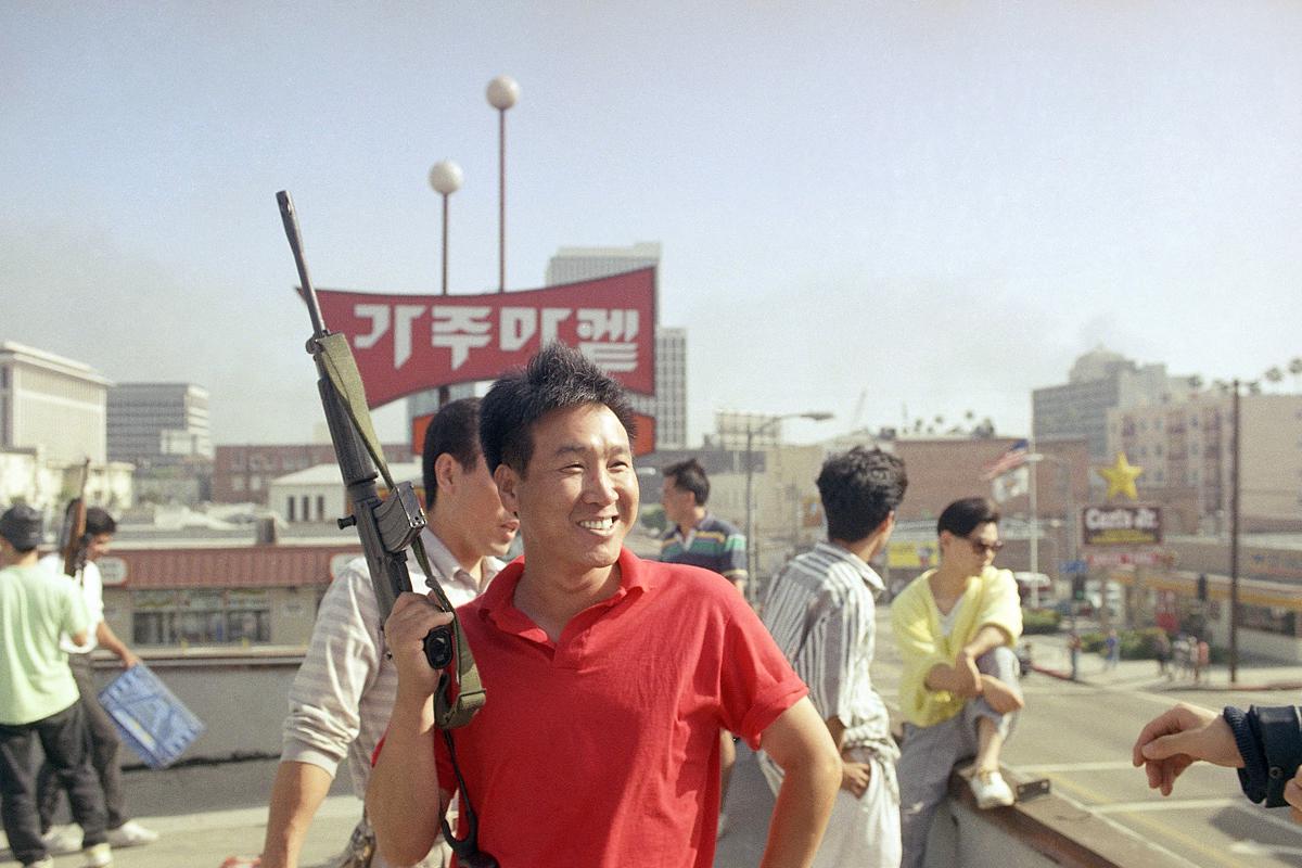 A Korean American carries a rifle to prevent rioters from entering a