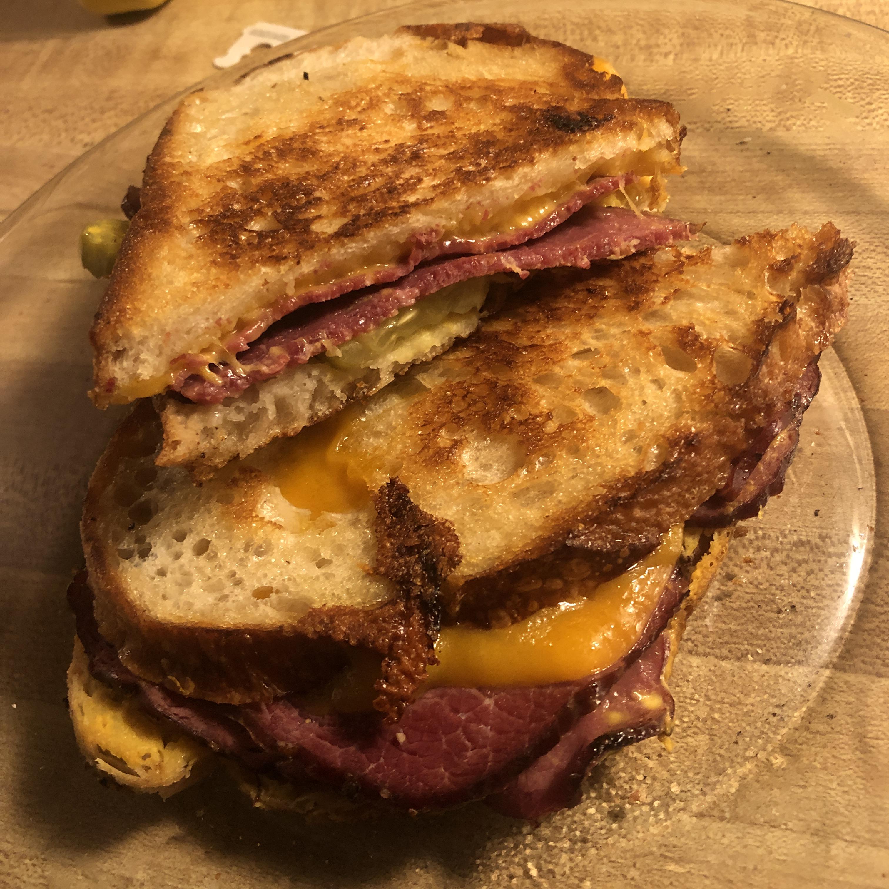 Grilled pastrami on sourdough with sharp cheddar, pickles, and mustard