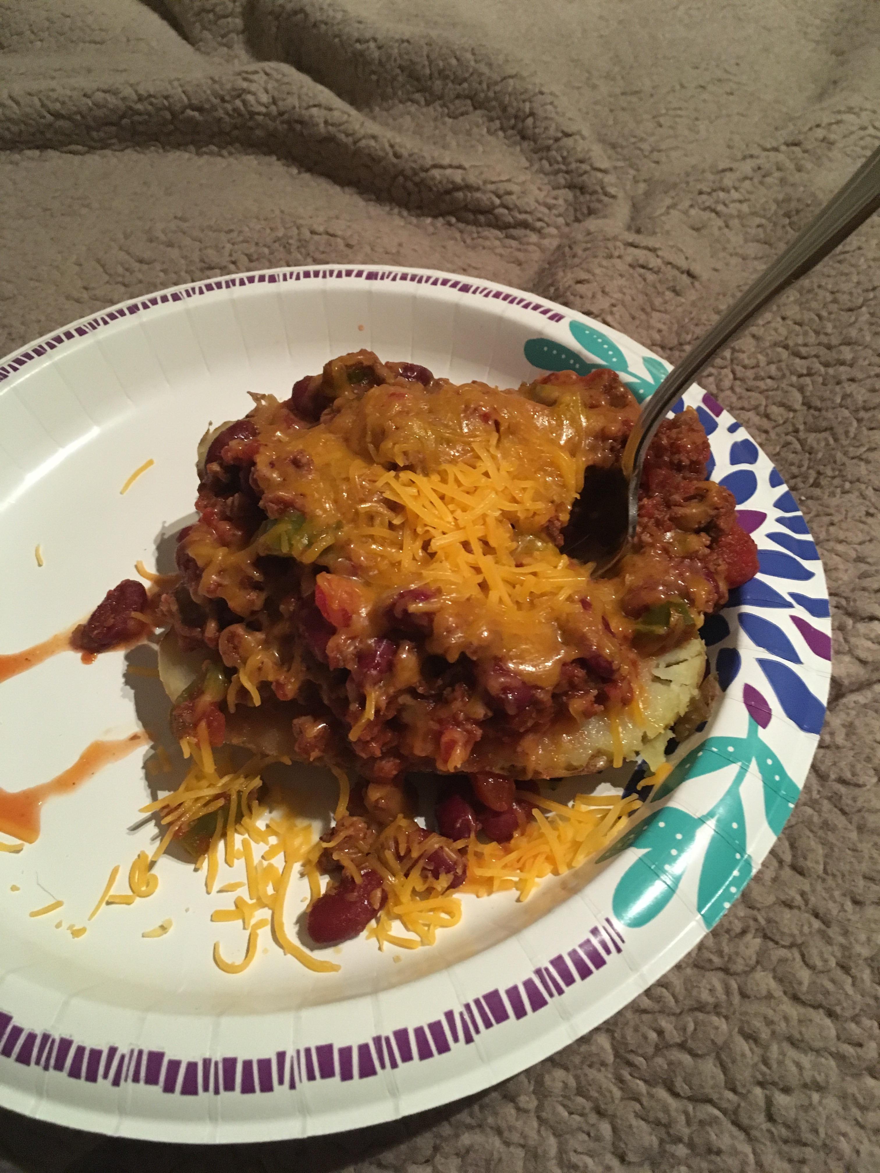 Microwaved and buttered potato with microwaved chili and cheese on top