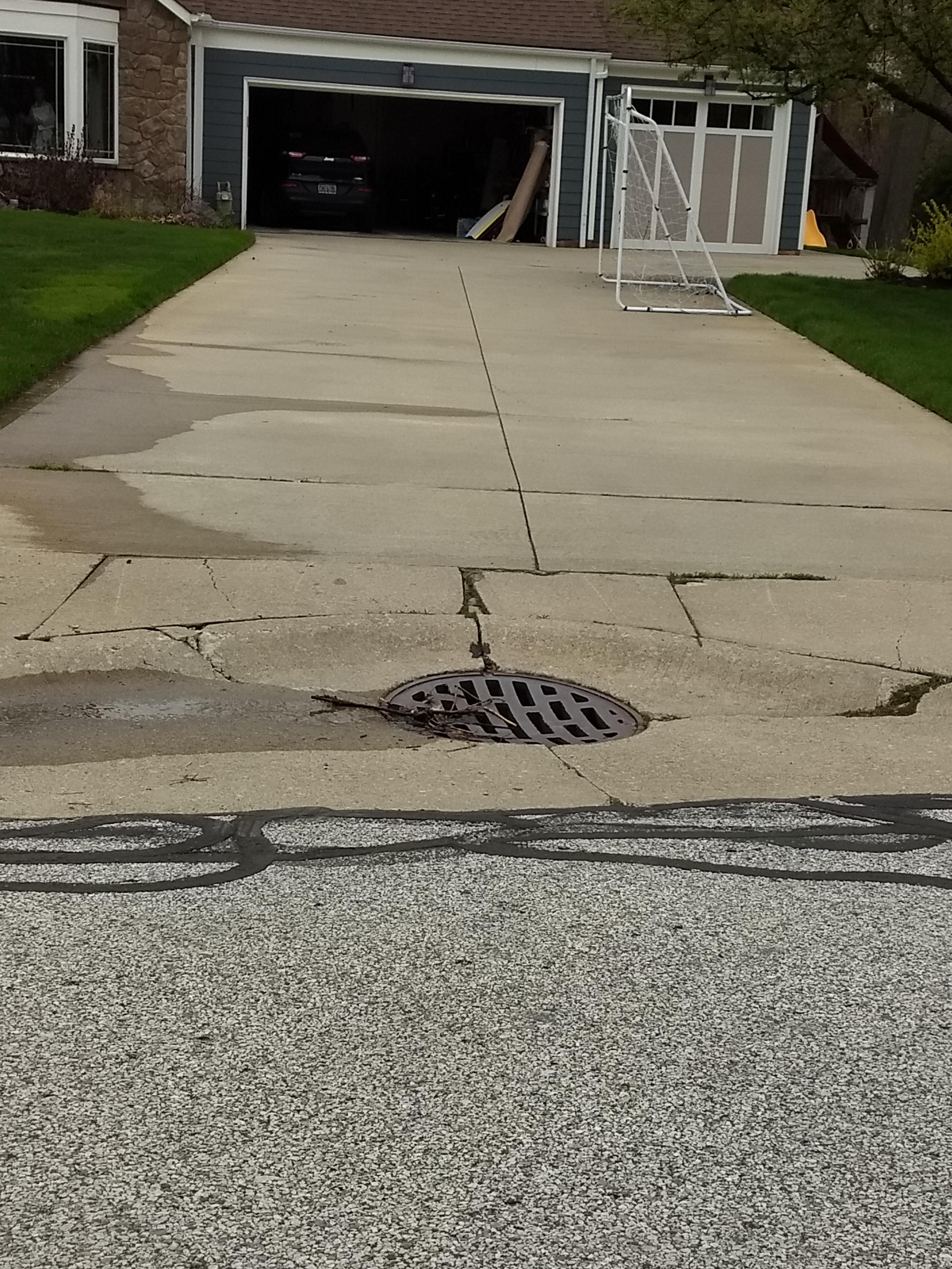 A Sewer Drain in the middle of the entrance to someone's driveway r