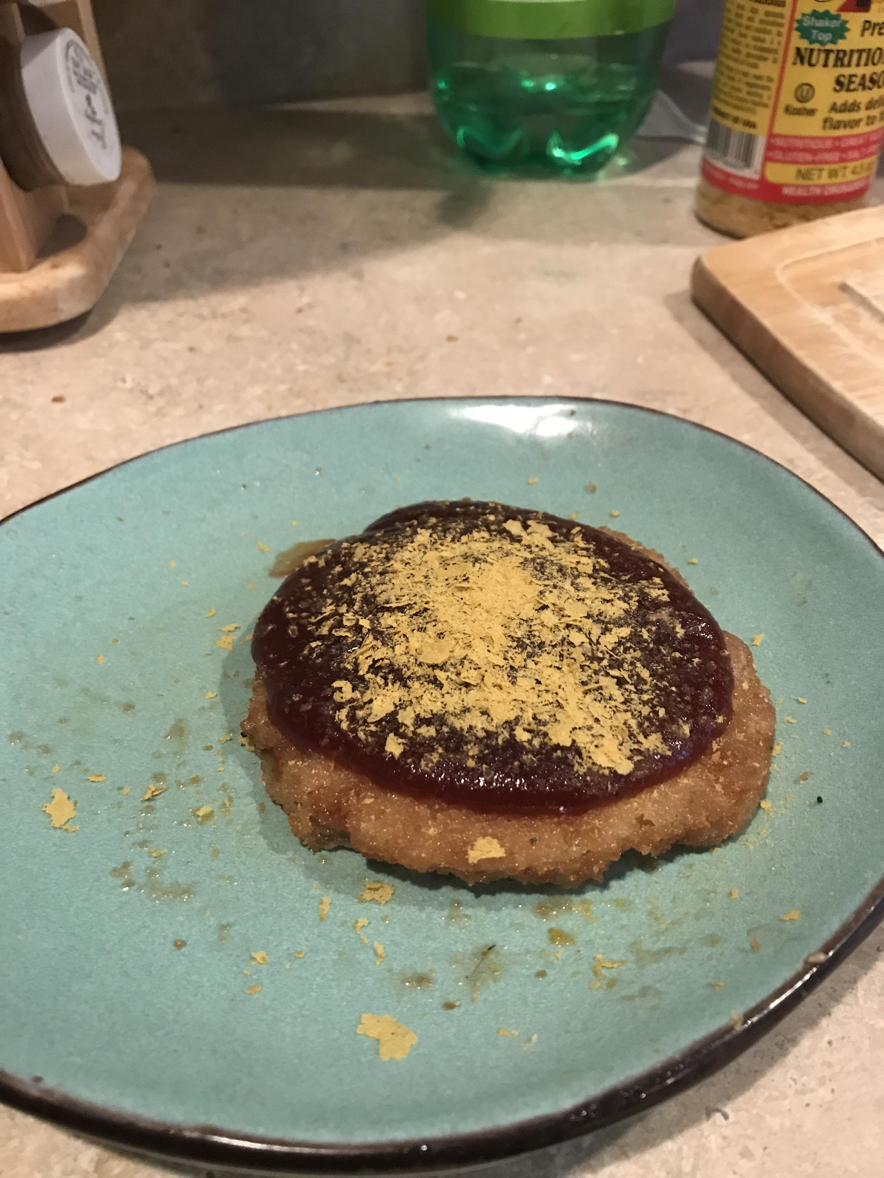 Meatless "chicken" patty with BBQ sauce and nutritional yeast topping