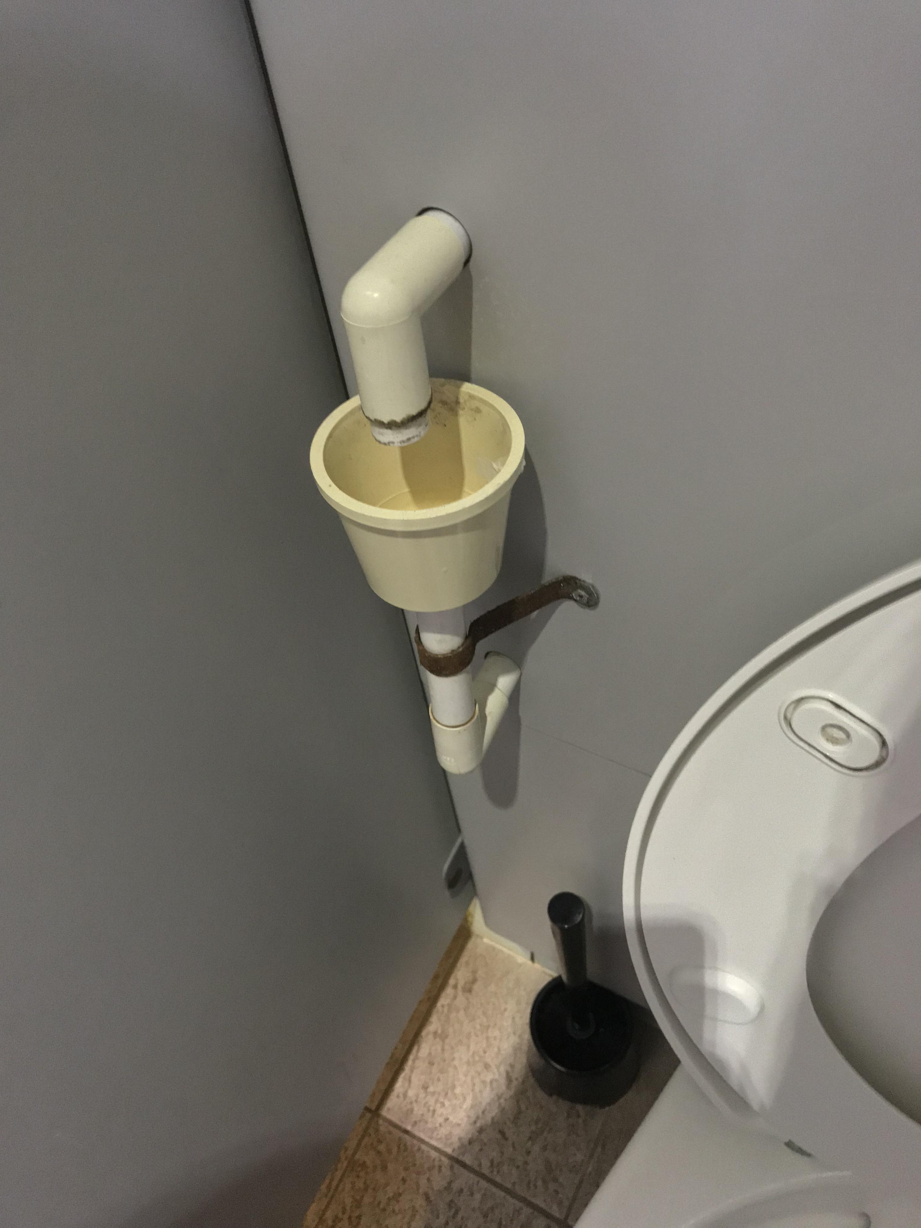 A pipe coming out of the wall, continuous drips of water into a cup