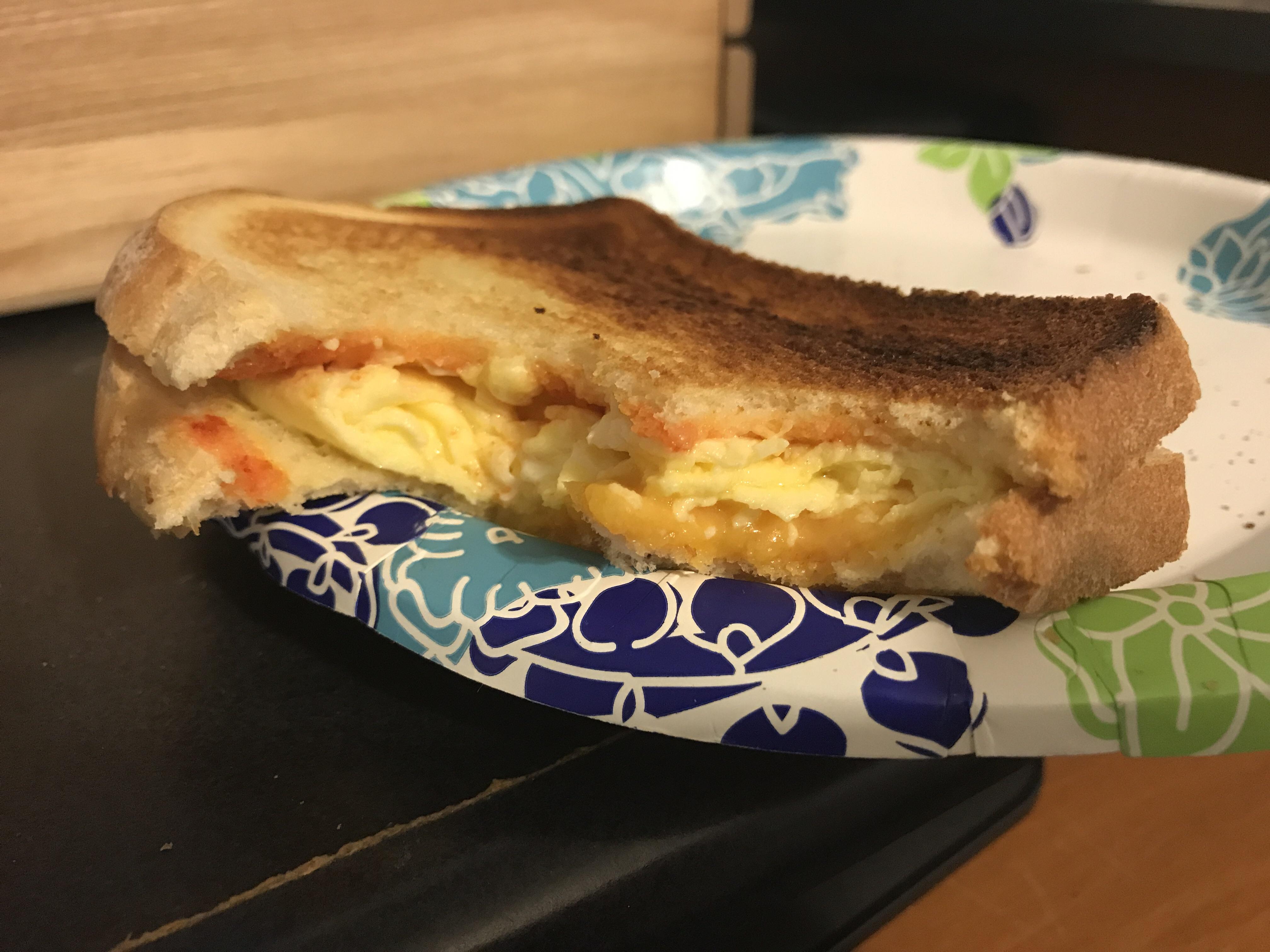 Homemade egg sandwich with cheddar cheese and Sriracha sauce on toasted