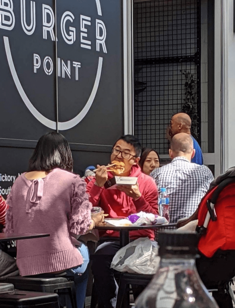 Man holding and eating a whole burger with chopsticks r/chopsticks