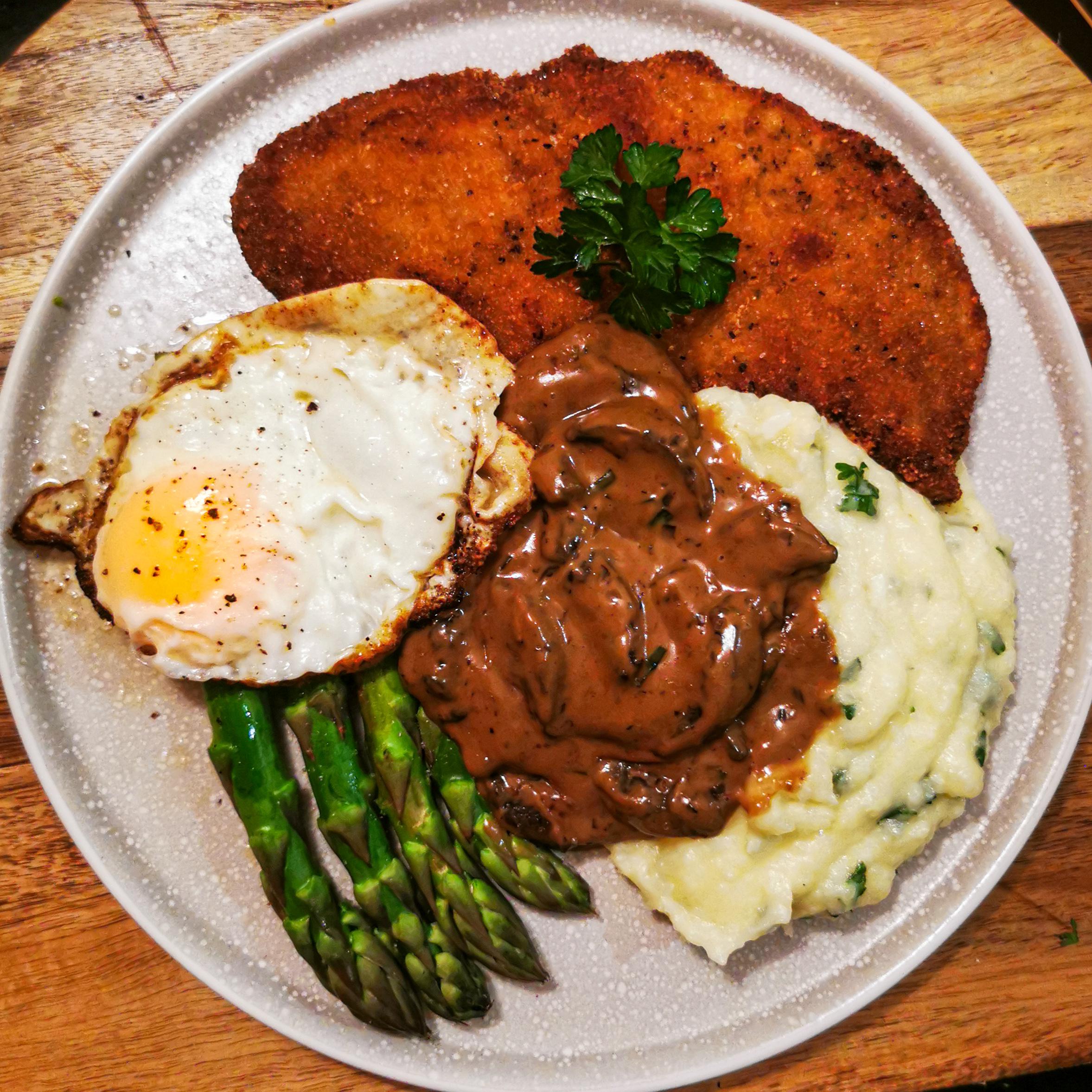 Veal Schnitzel with potato mash, steamed asparagus, fried egg, and