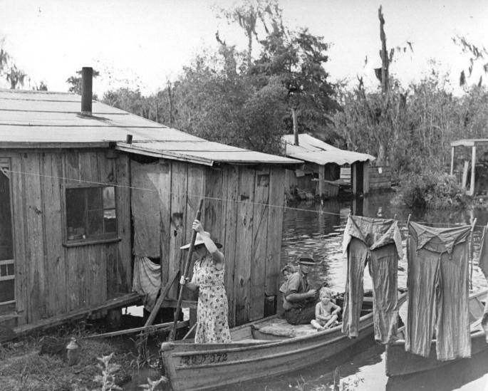 A Cajun family canoeing home to their shack on the Louisiana bayou