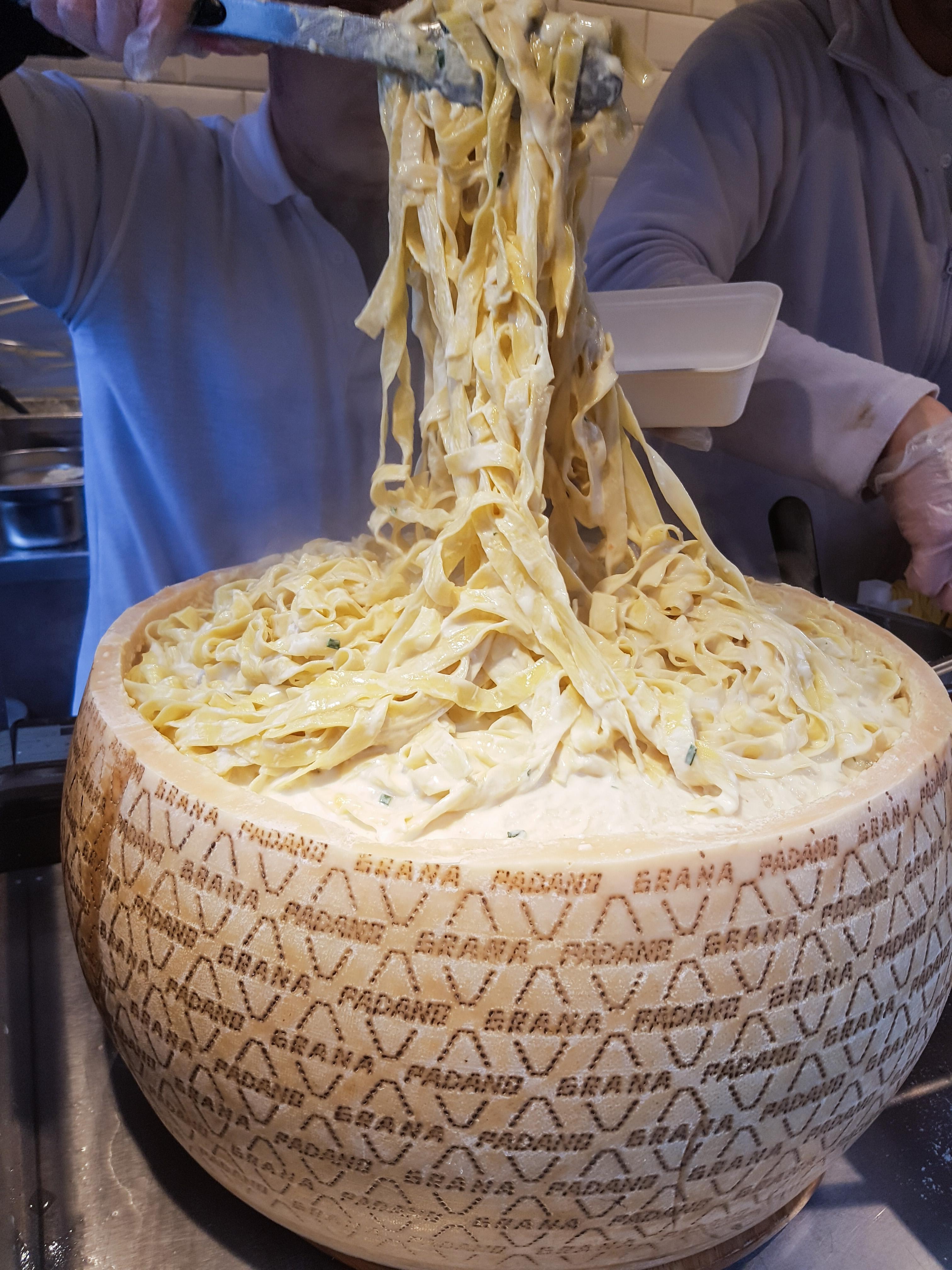 Italian fettuccine pasta drowned into a huge cheese wheel. London