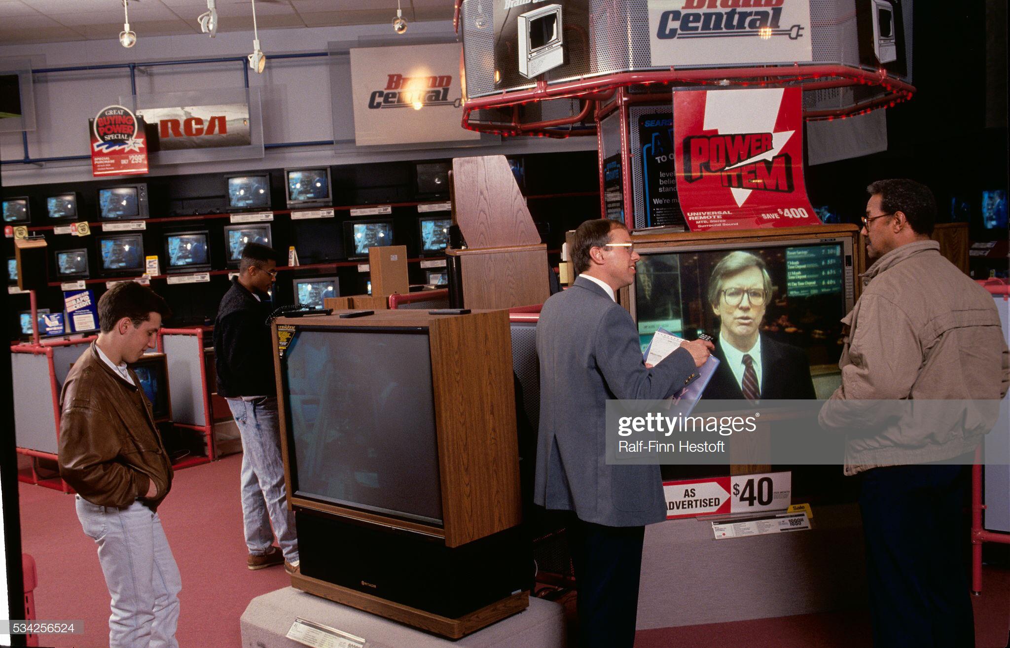 Shoppers looking at big screen television sets at a Sears Brand Central