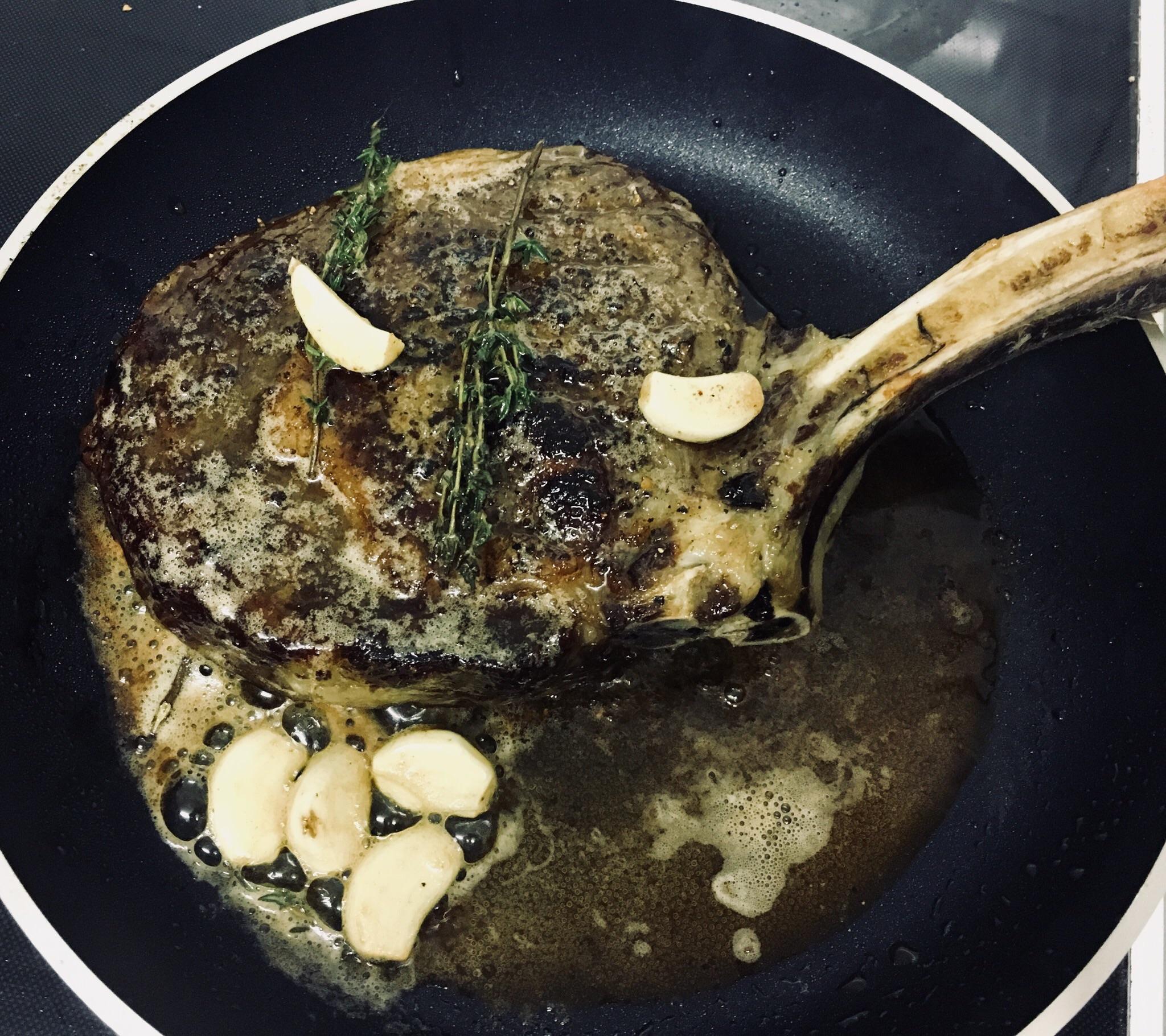 Tomahawk ribeye seared in pan with garlic and rosemary and lots of