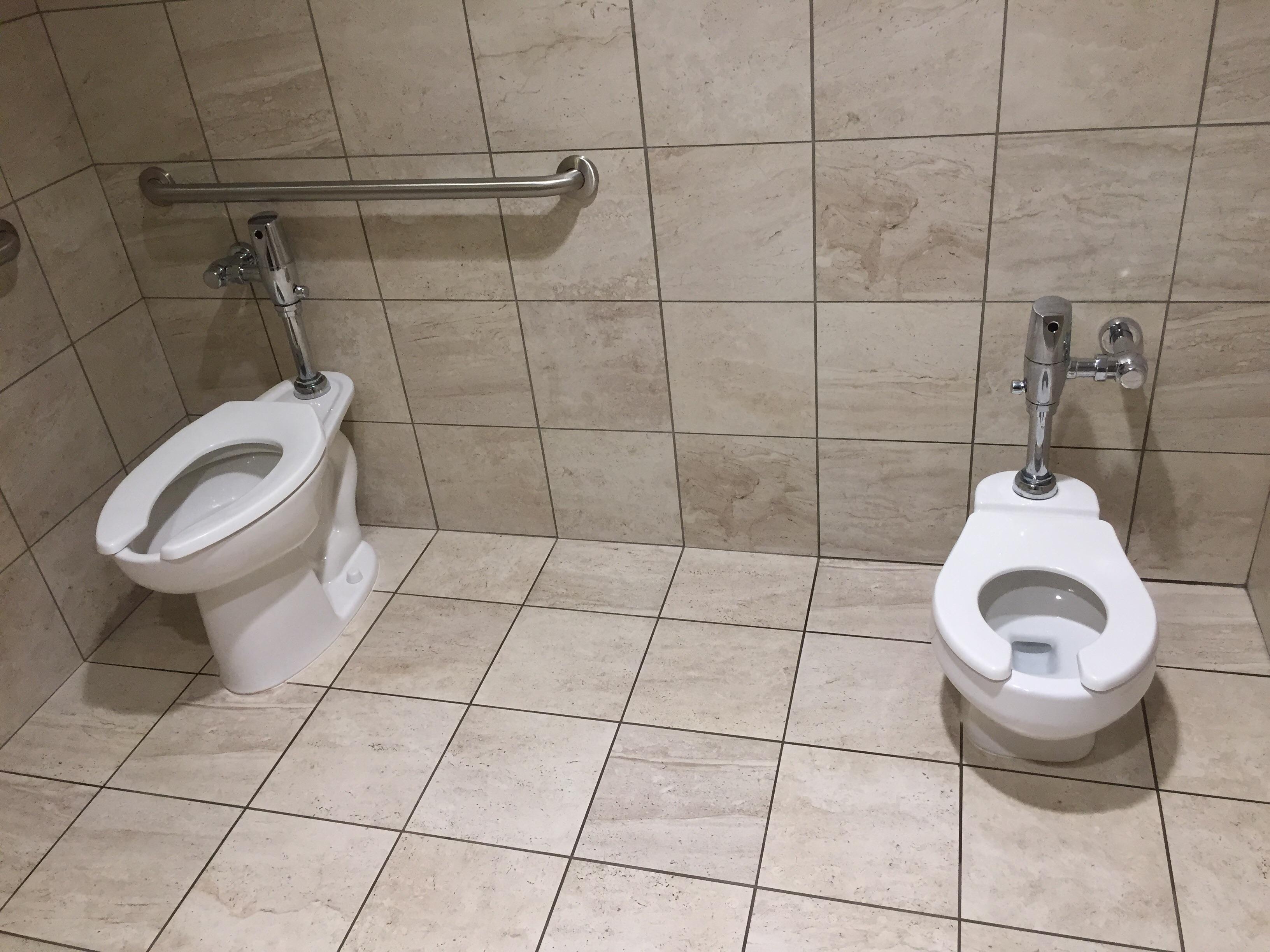 This public restroom has a toilet for toddlers next to a normal sized