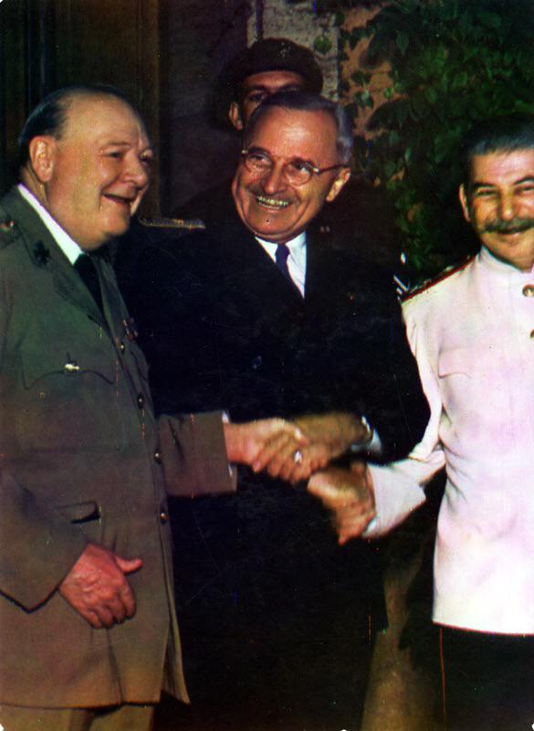 In a triple handshake, President Harry S. Truman holds the hands of