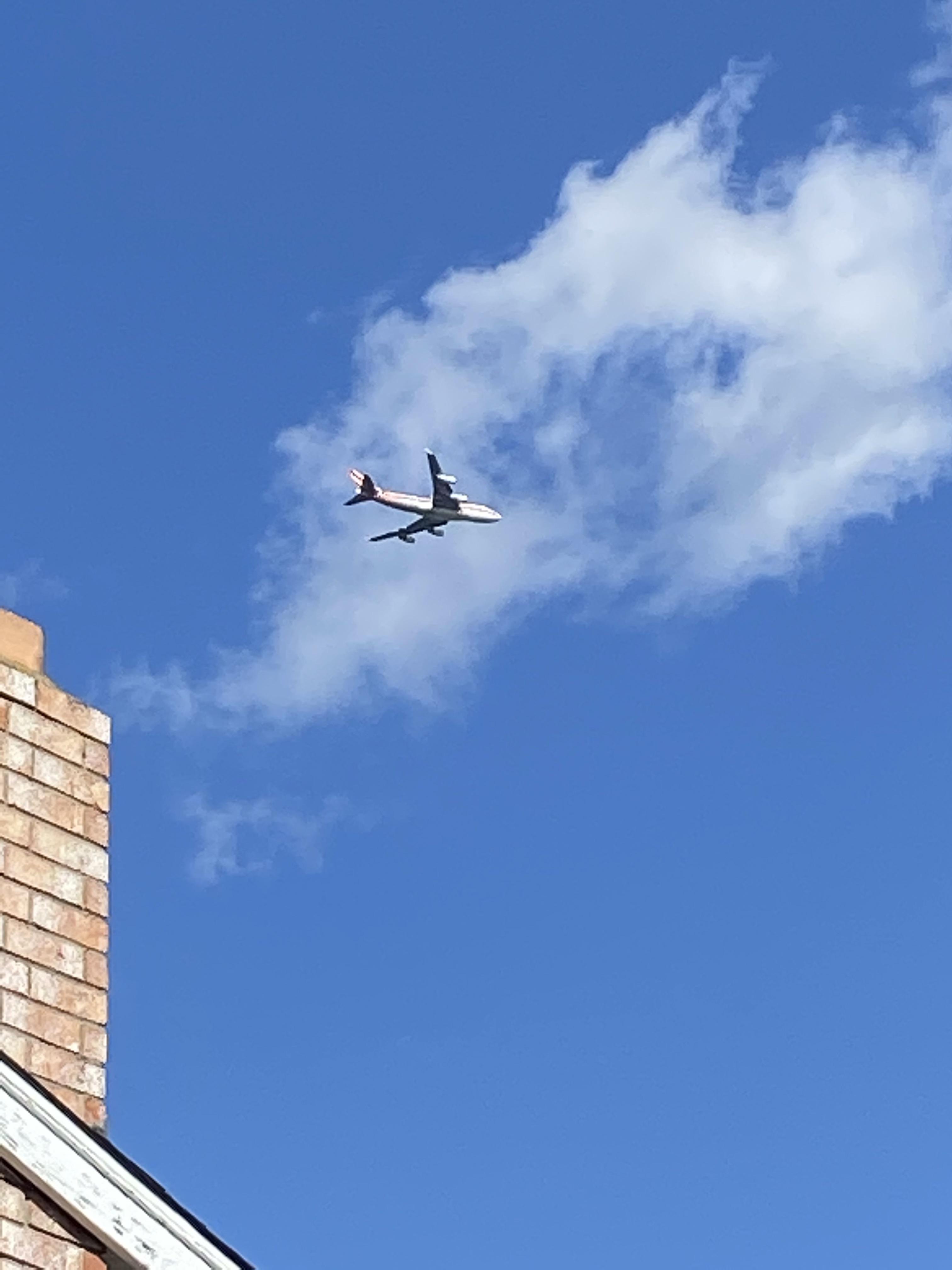 Low flying white plane with red stripe over California residential