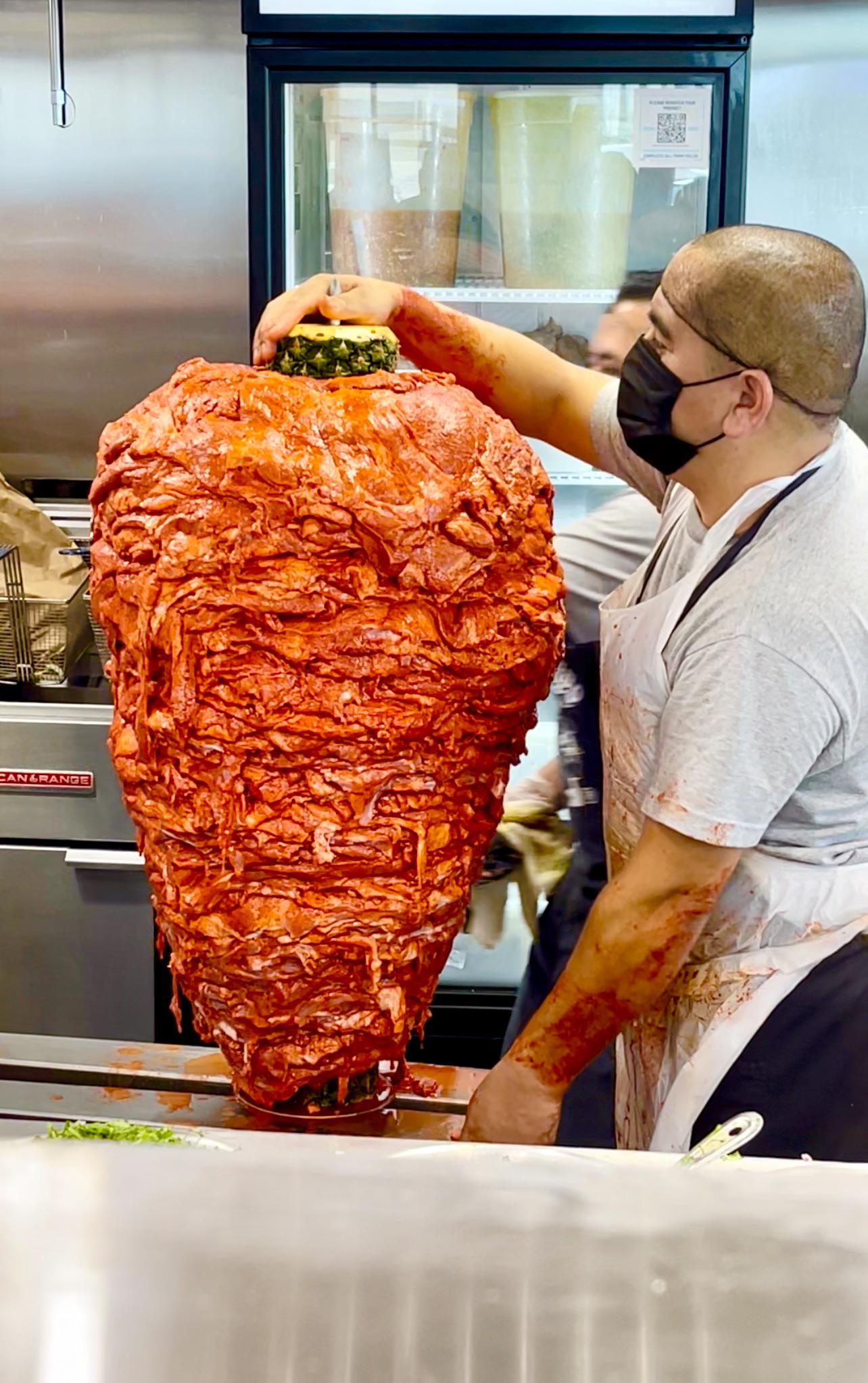 Al pastor meat about to be loaded on a vertical spit, he’s waiting for
