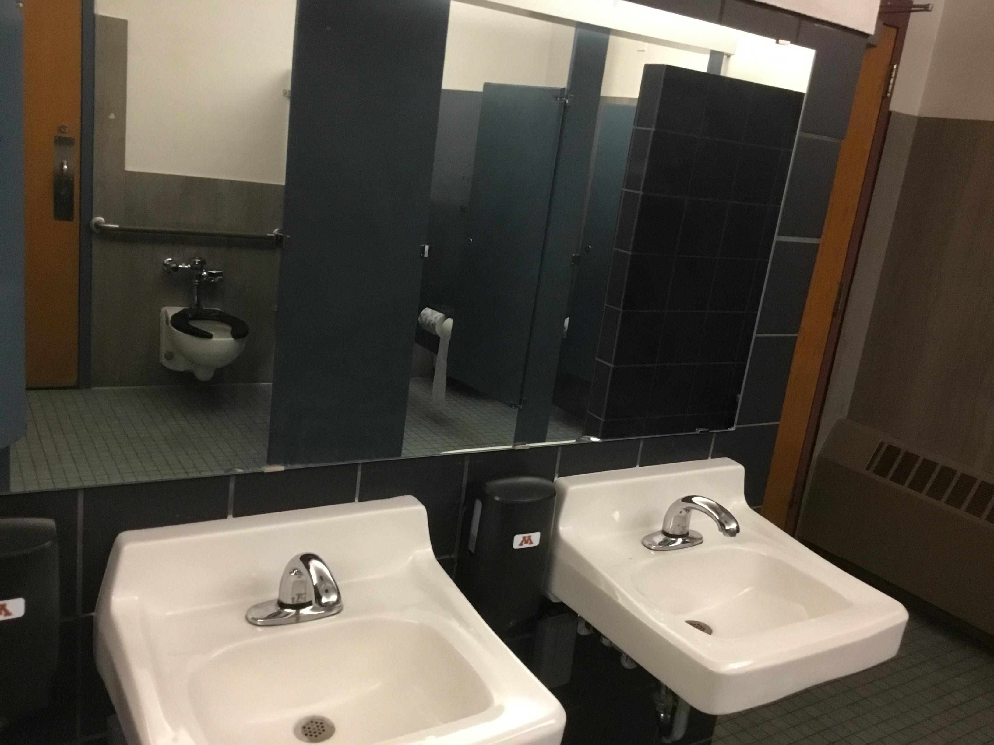 This bathroom has a closet in a stall and the soap dispensers are lower