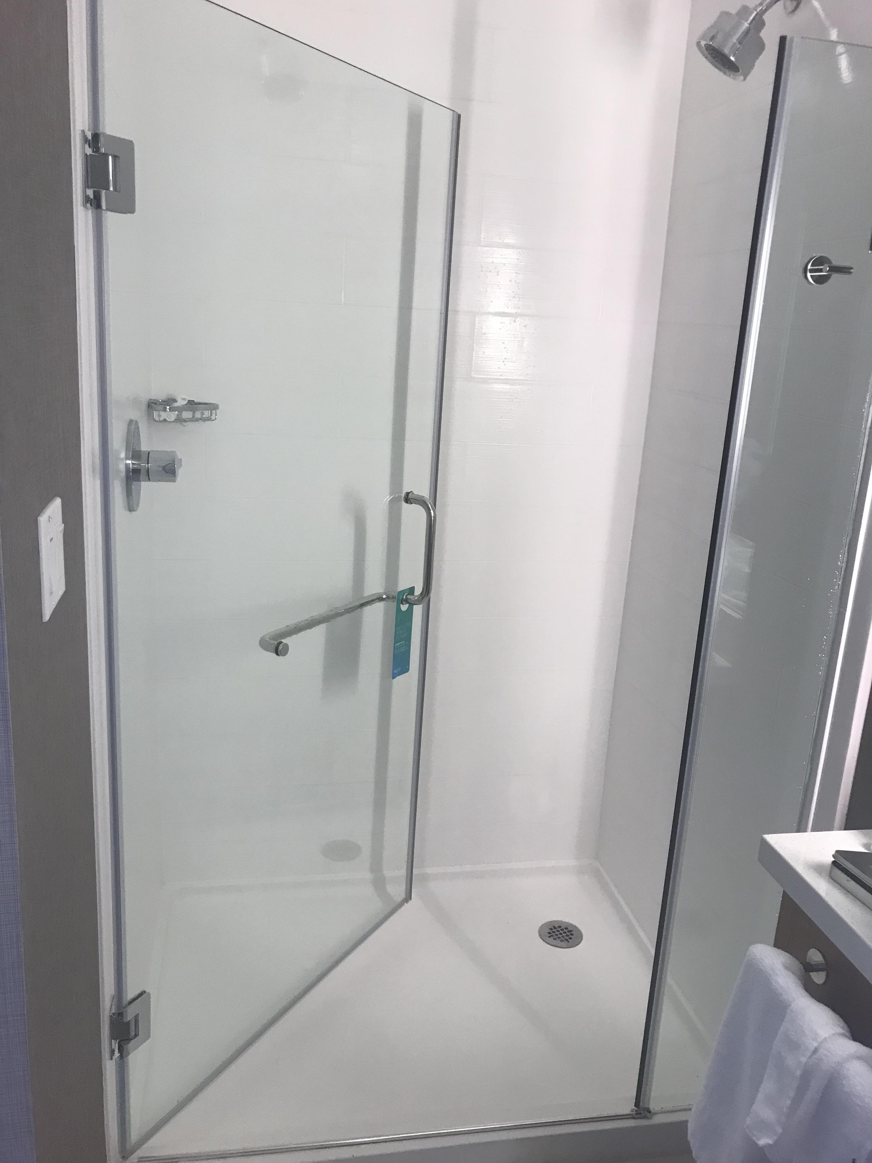 This shower opens inward covering the controls and has shower head on