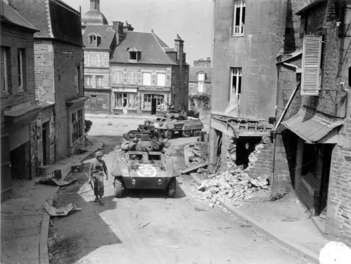 Two M8 armoured cars of the 82nd Armored Reconnaissance Battalion patrol in the streets of Saint