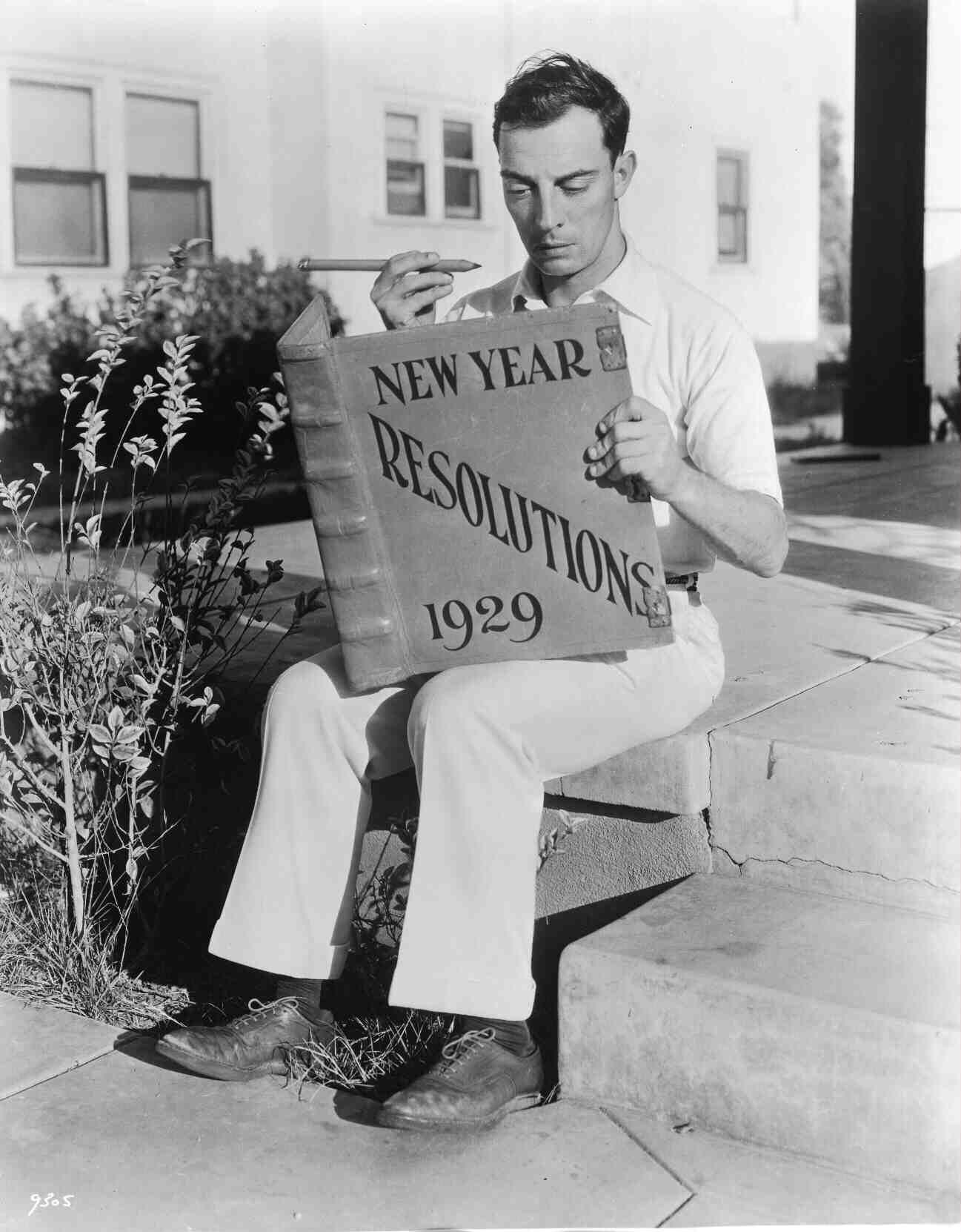 Buster Keaton reading an oversized book on New Years resolutions 90