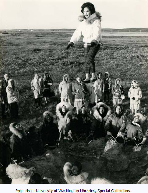 Eskimo woman in mid-air during traditional Blanket Toss, Alaska, probably between 1960 and 1970