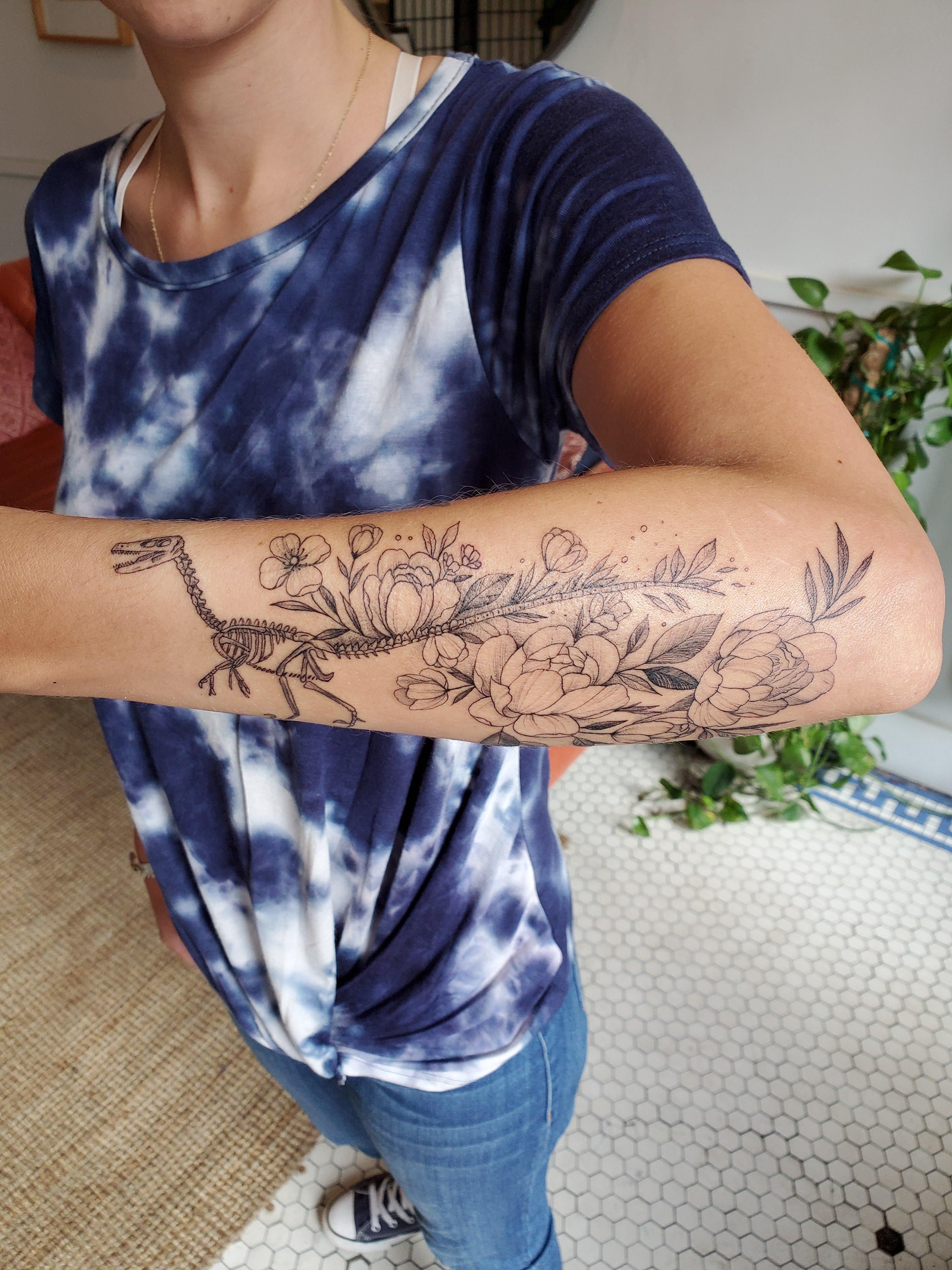 Velociraptor and flowers done by Hannah Kang at Nice Tattoo Parlor in