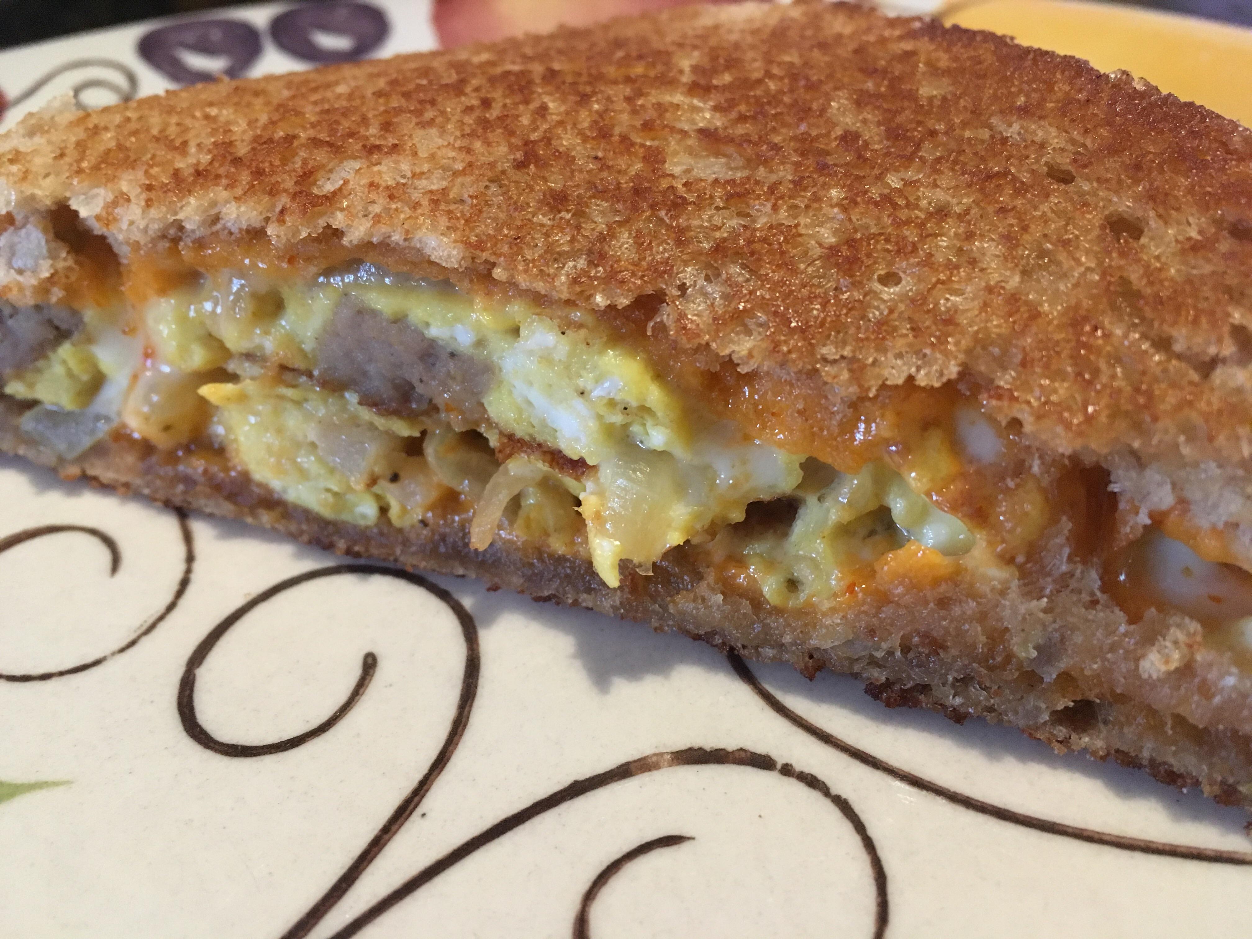 Grilled egg & cheese with maple sausage, onions & sriracha mayo