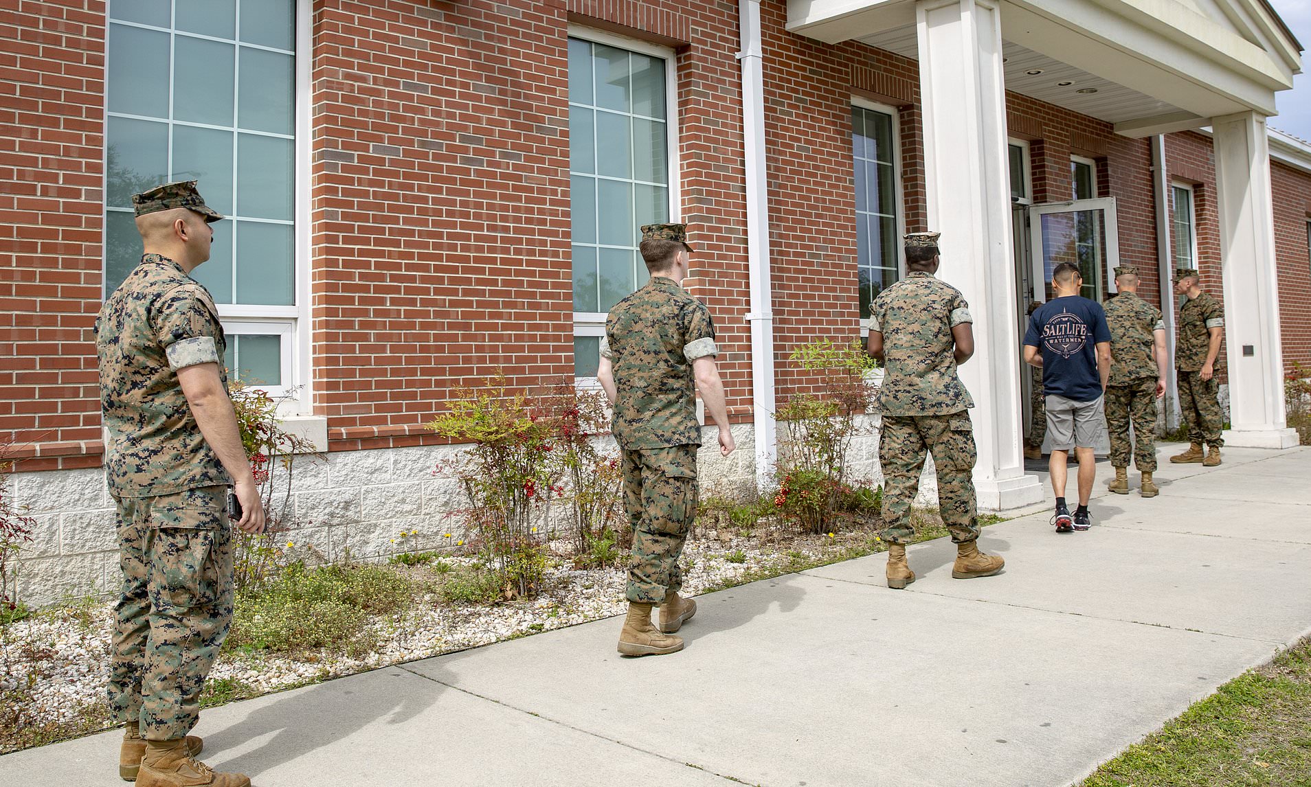 U.S. Marines and sailors line up six feet apart outside a chow hall at