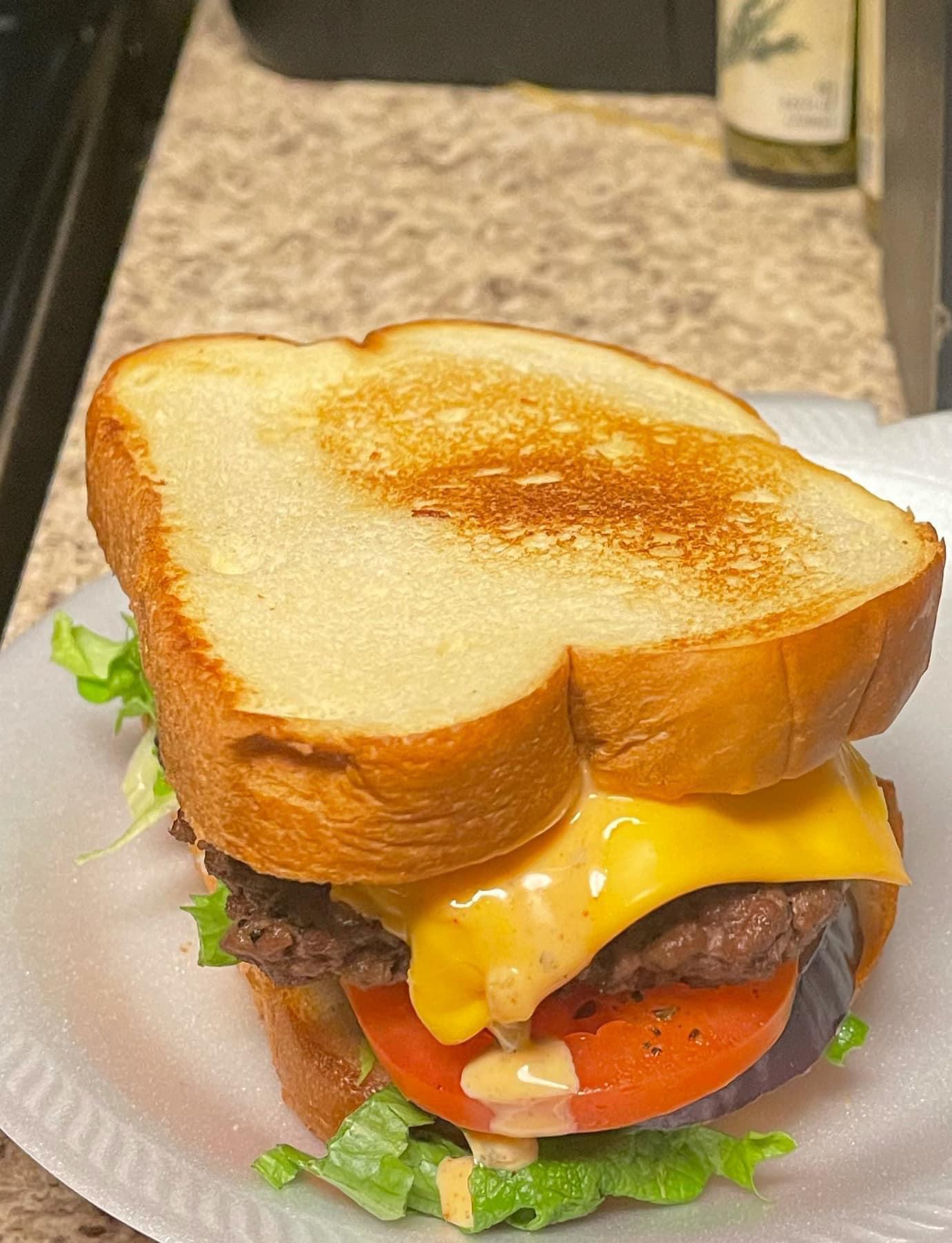 Cheeseburger on a toasted bun with sauce, lettuce, and tomato. r/FoodPorn