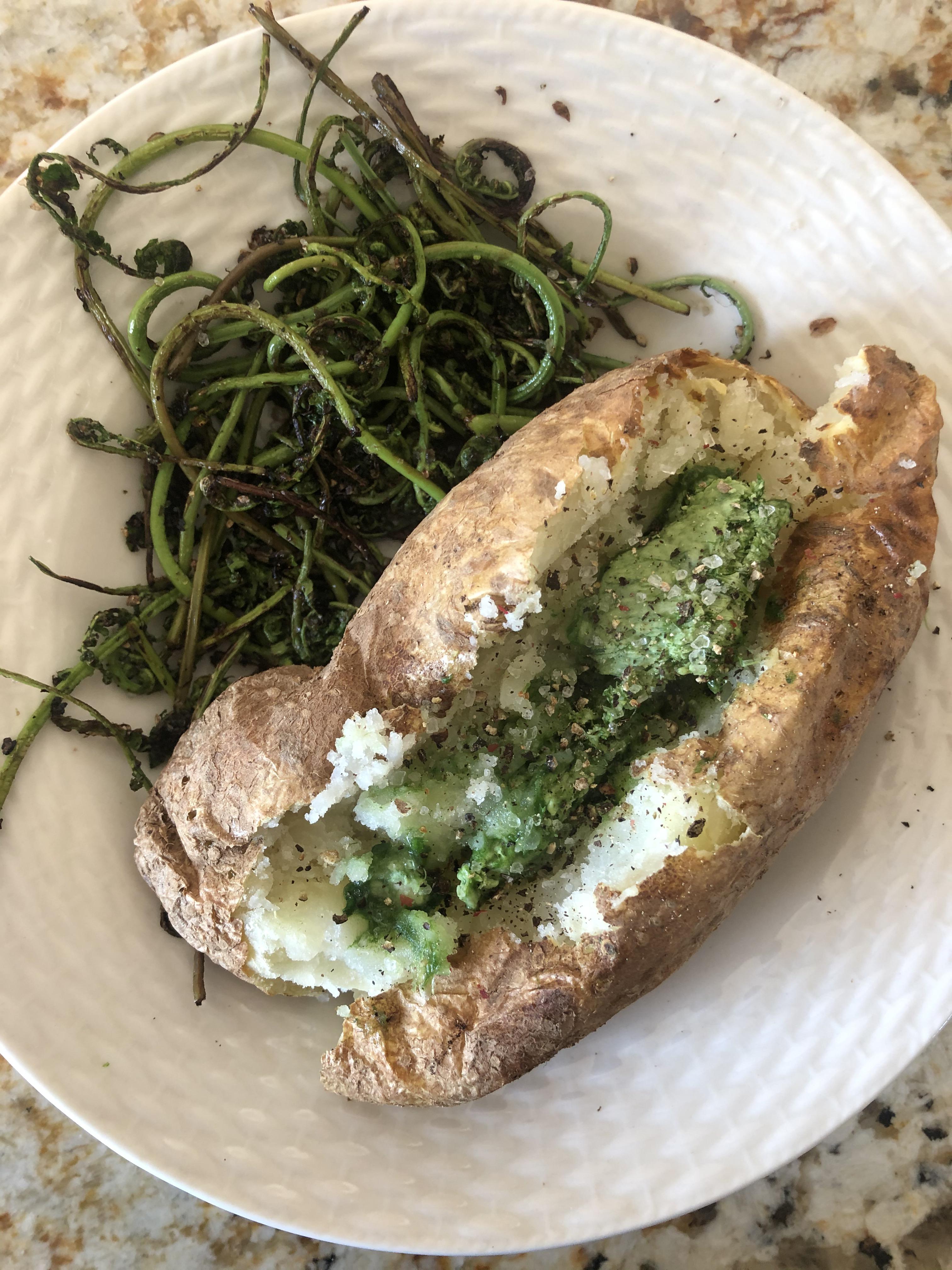 Baked potato with ramp butter and a side of sautéed fiddleheads r