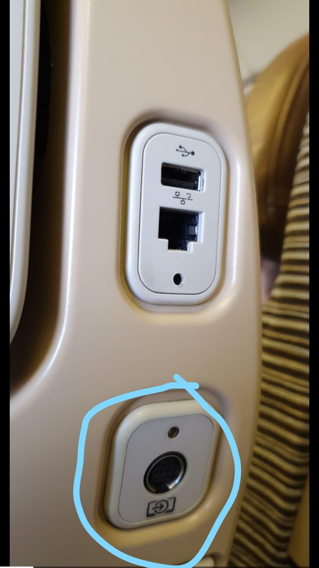 The port in the circle, spotted on the back of a plane seat on a long