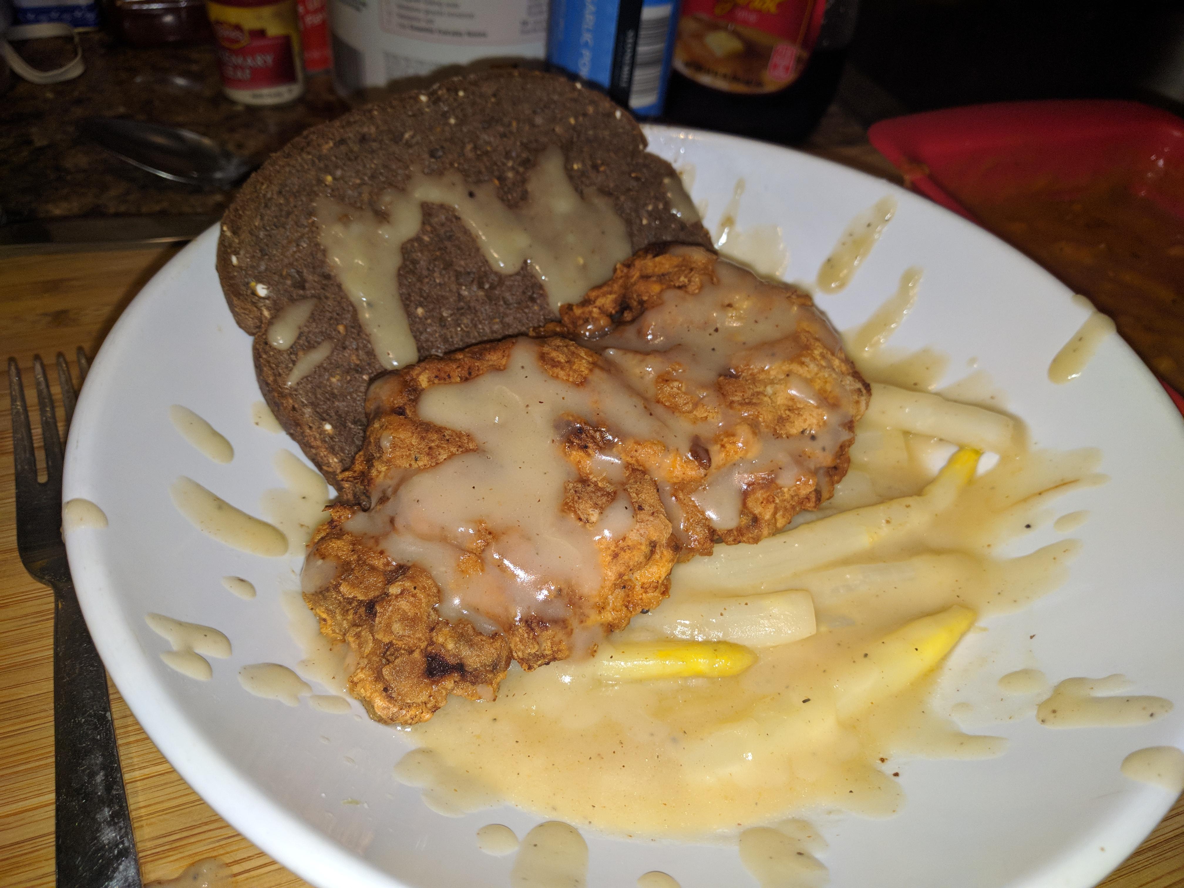 Gravy spackled fried chicken floating on a pool of sauteed white