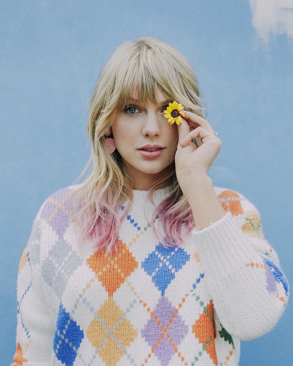 Taylor Swift in cute sweater holding a flower Celeblr