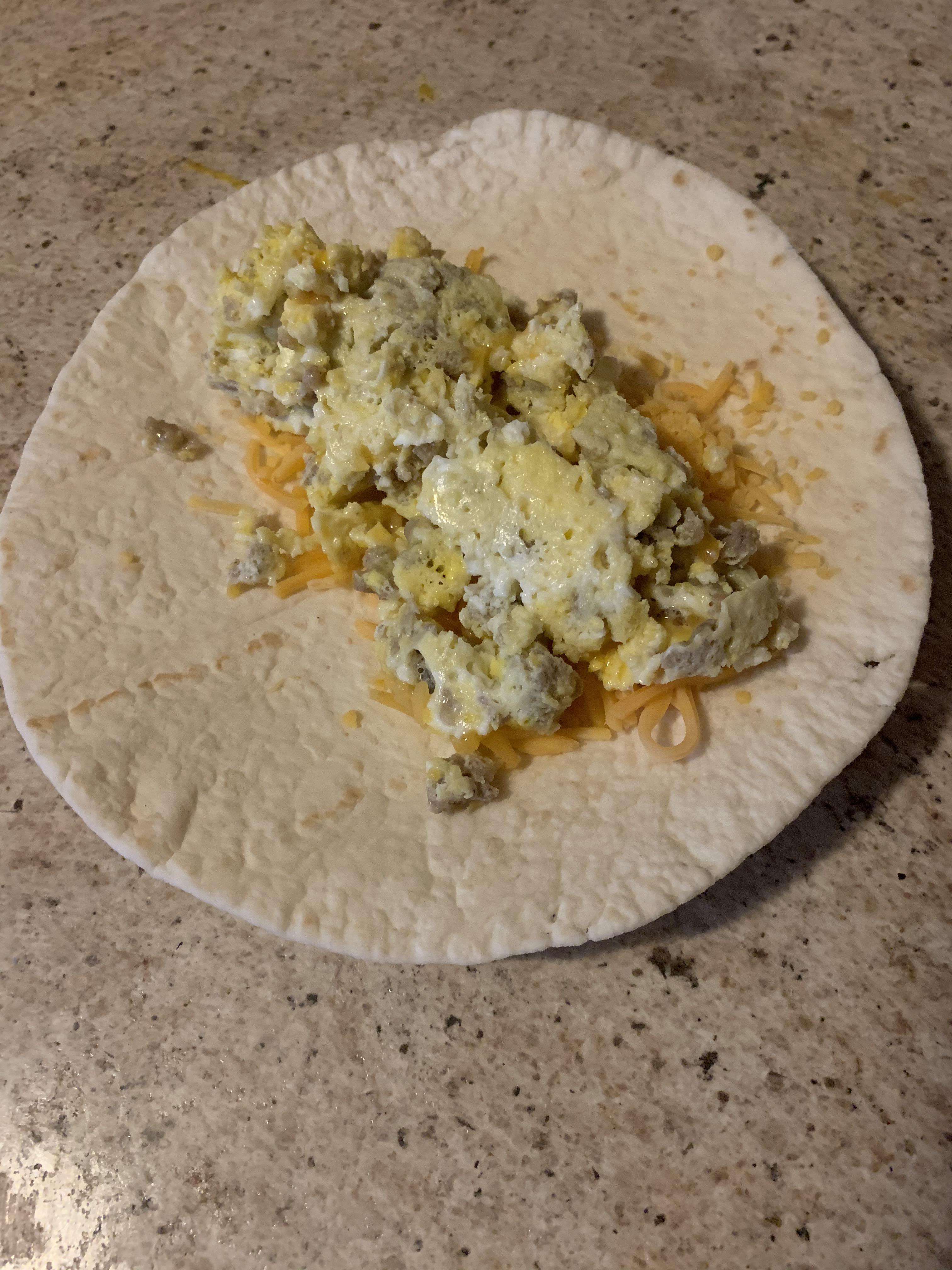 Microwave scrambled egg, leftover sausage, and shredded cheddar in a