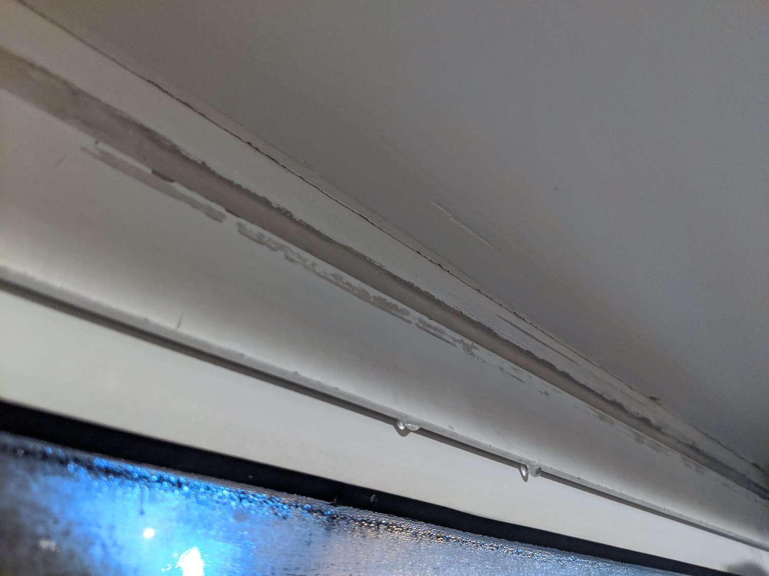 Finishing drywall that abuts against metal frame prone to condensation