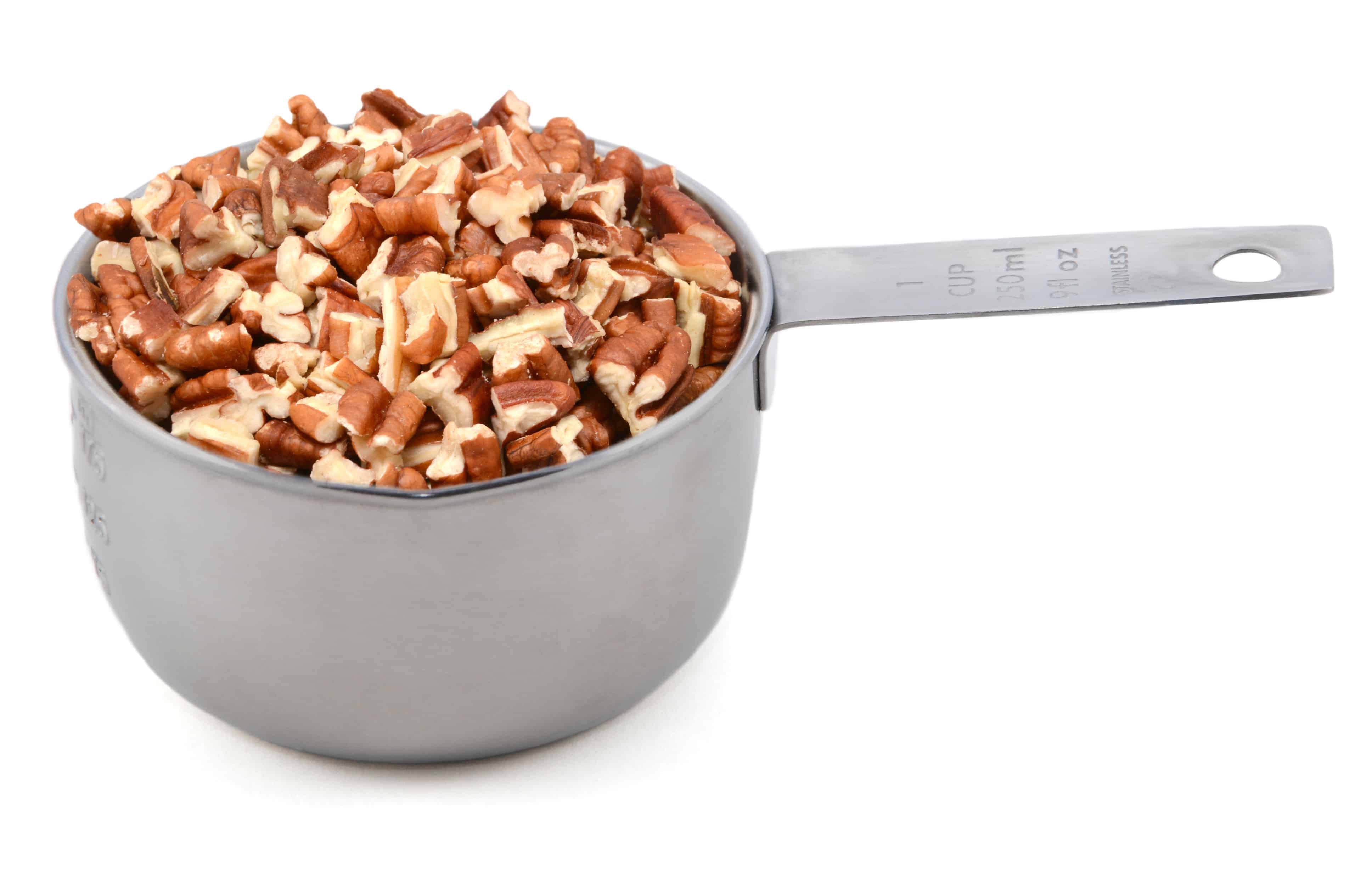 Chopped pecan nuts in a metal cup measure _ ILovePecans