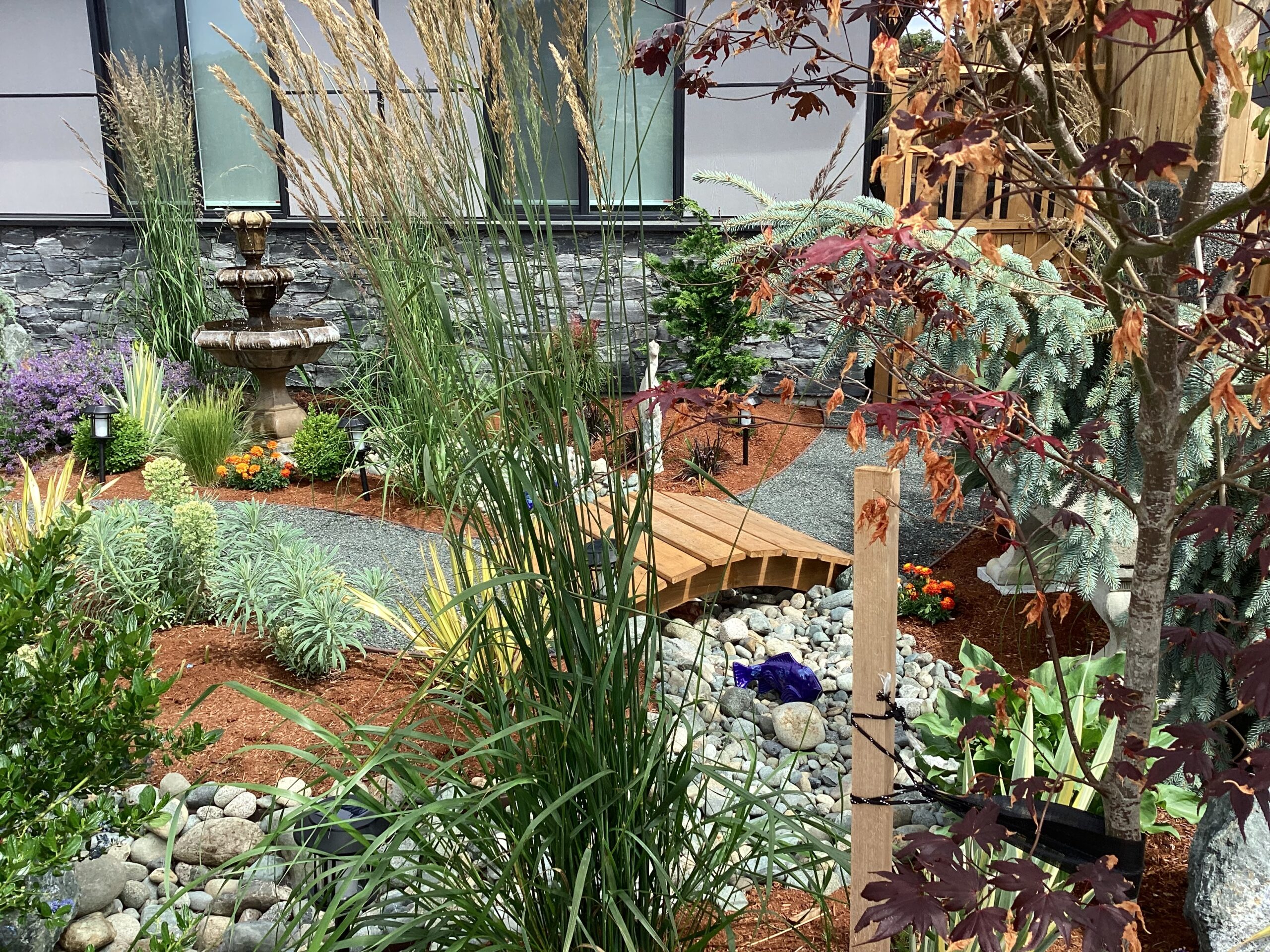 dry stream bed cutting through a garden with ornamental grass and trees