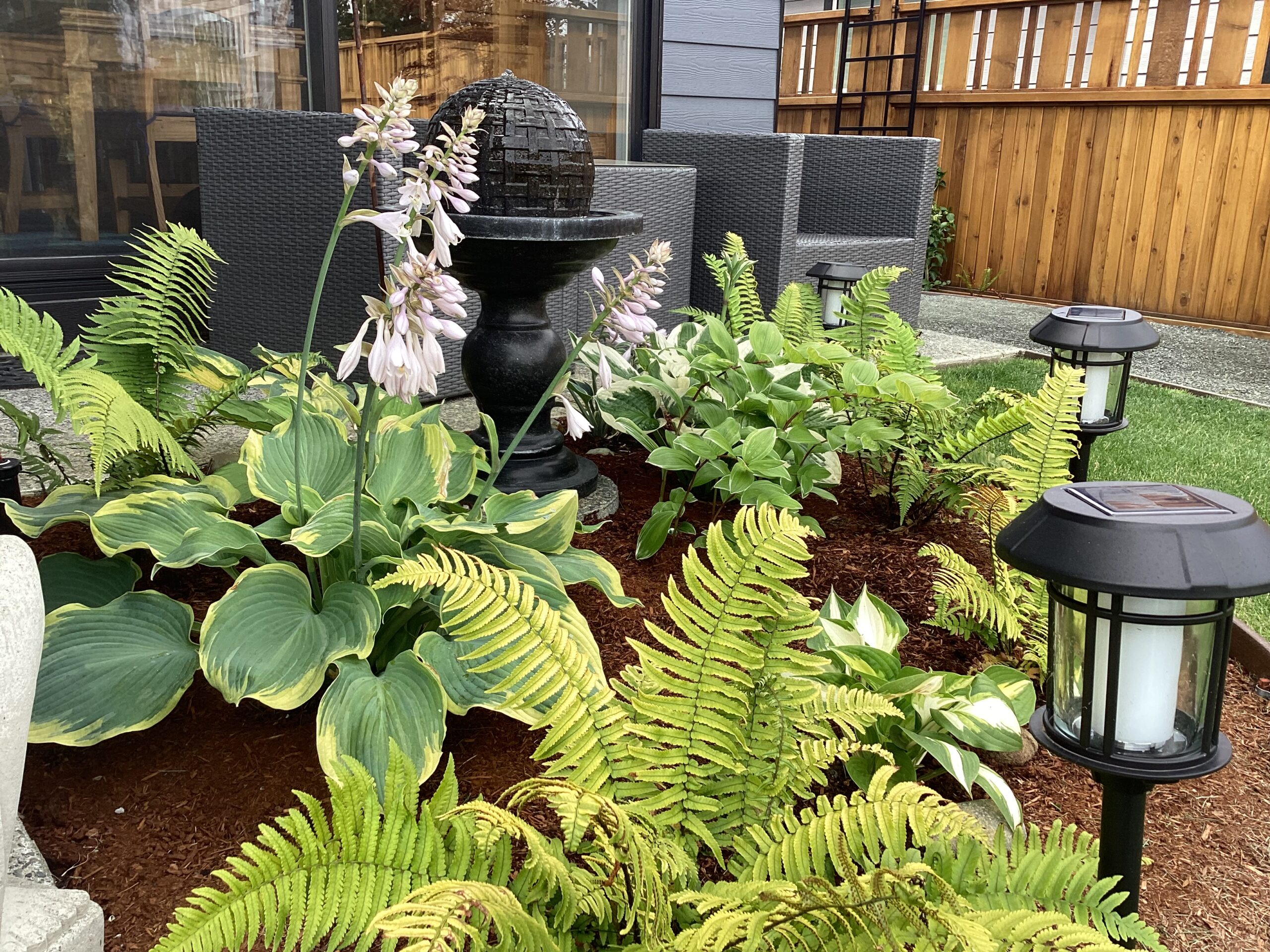 small shade garden next to seating area in the garden