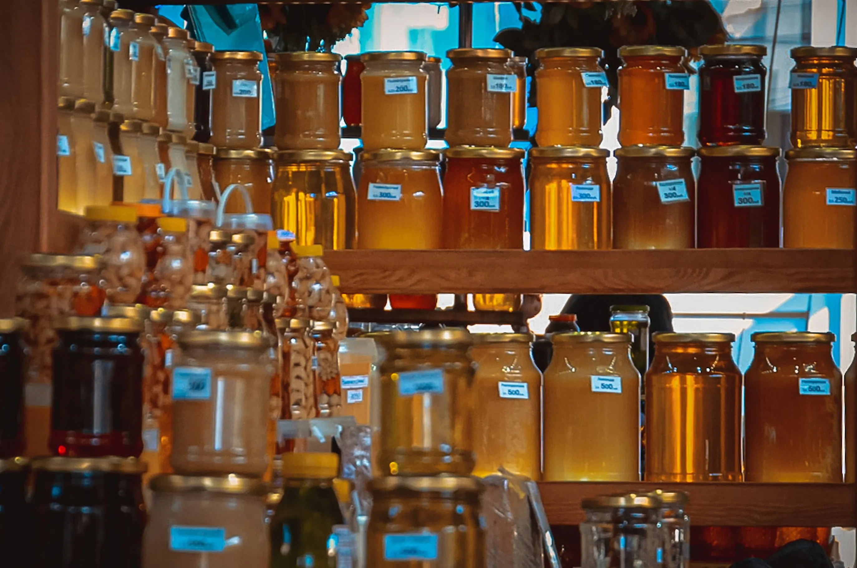 A vibrant collection of honey jars on wooden shelves, capturing the golden hues and natural sweetness.