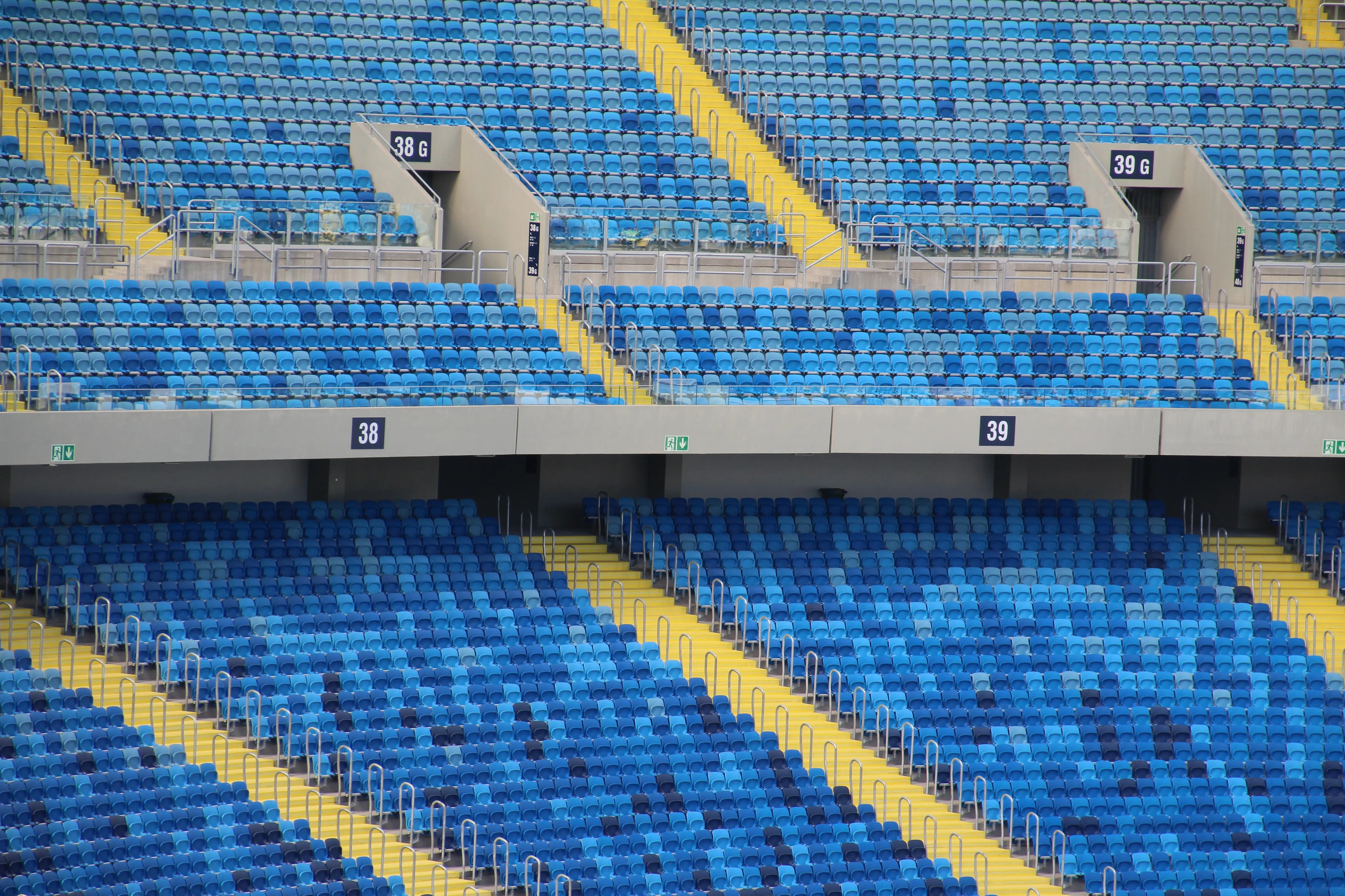 Rows of empty blue seats in a large sports stadium, showcasing a geometric pattern and tranquil atmosphere.