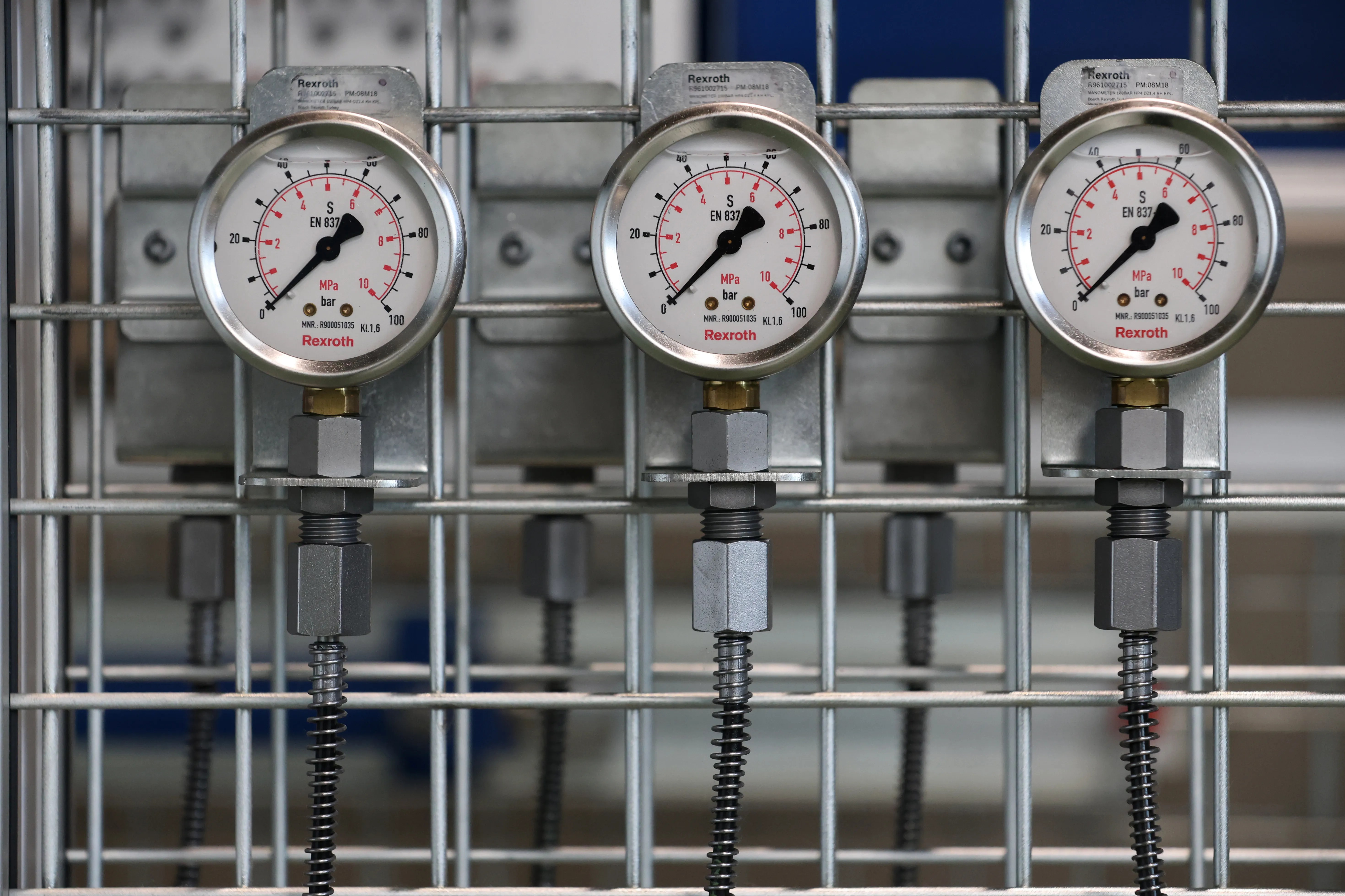 Close-up of industrial pressure gauges mounted on a metal grid in a factory setting.