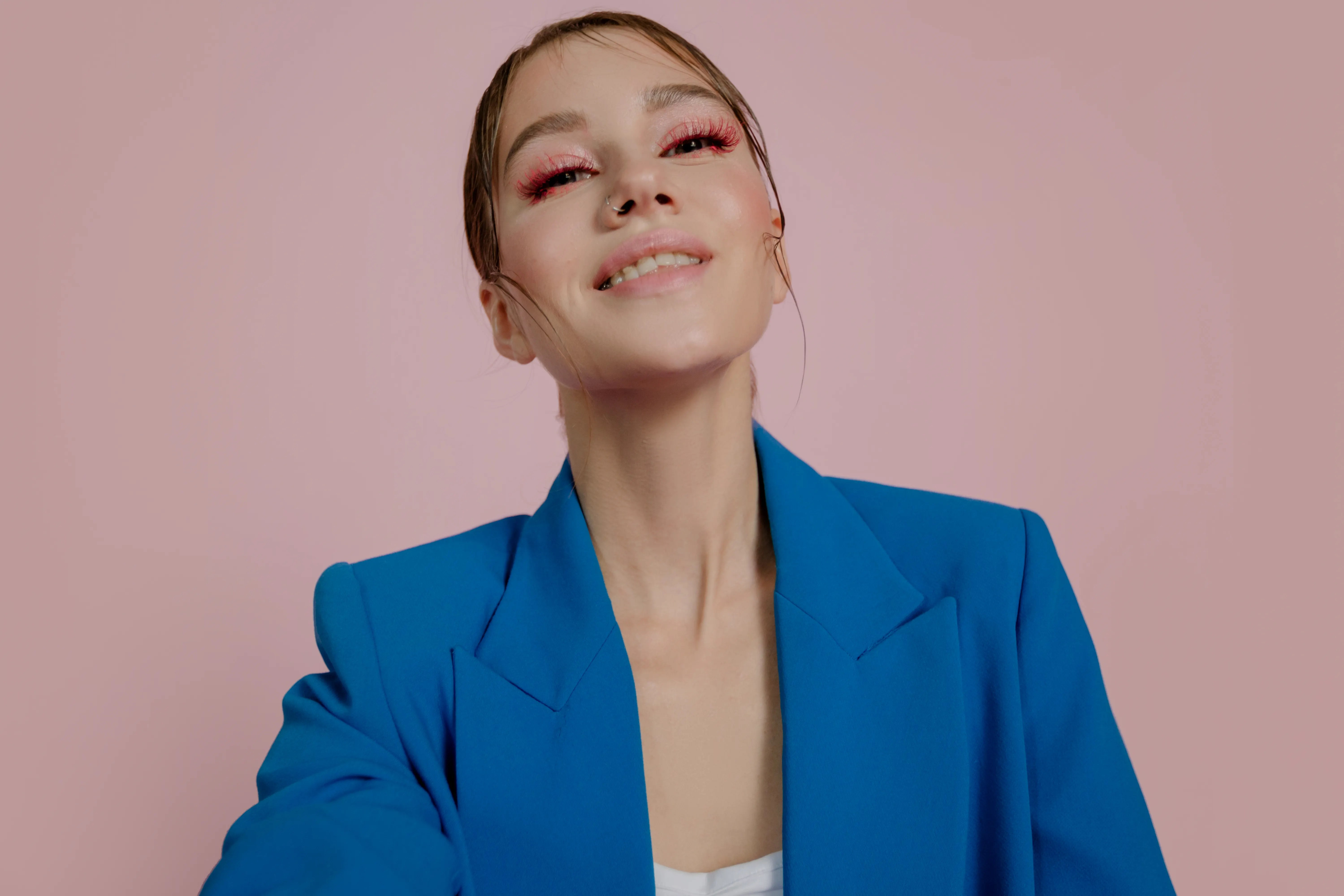 Stylish portrait of a woman in a blue jacket with pink background.