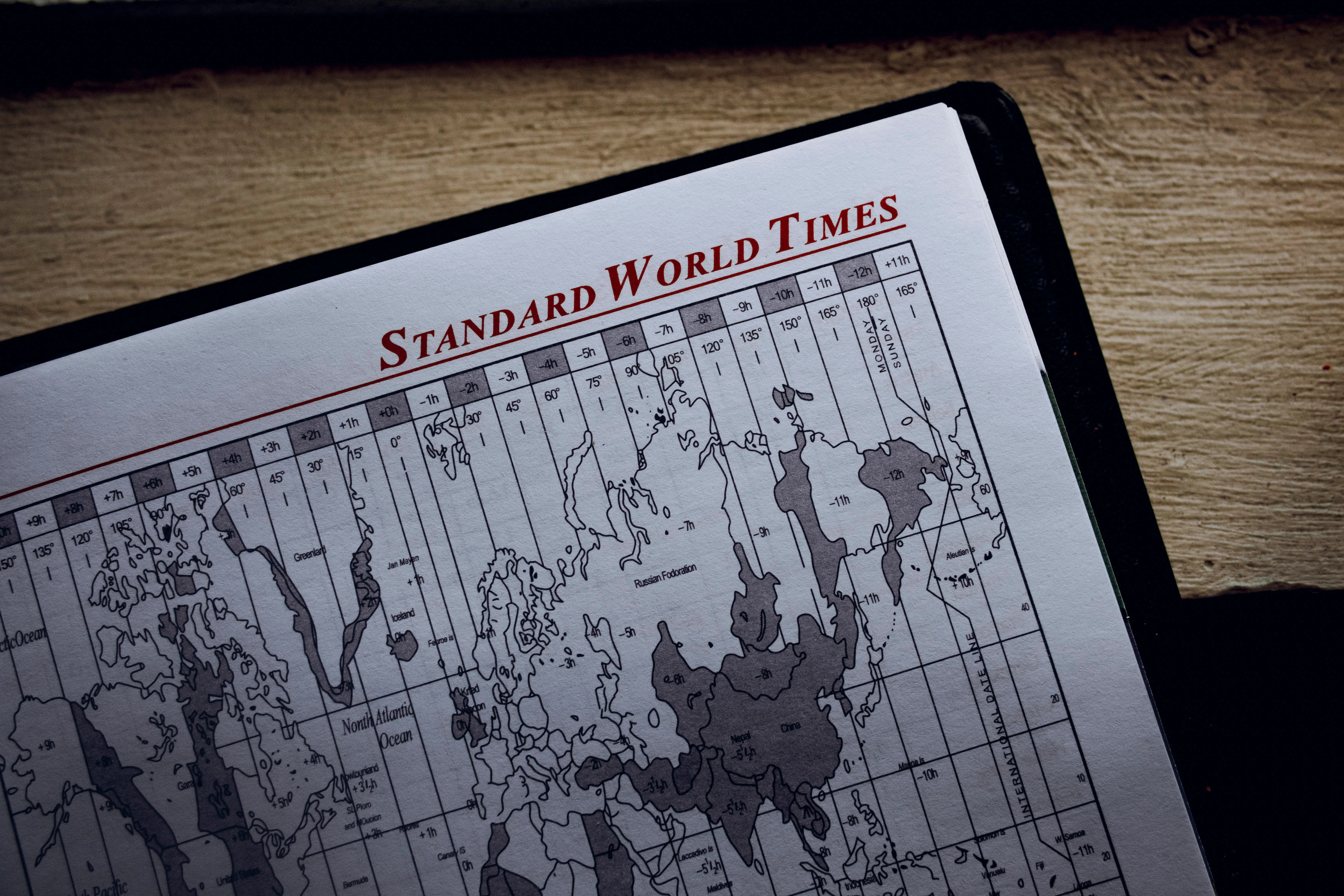 Top view of time zone illustration on page of agenda with inscription on wooden surface