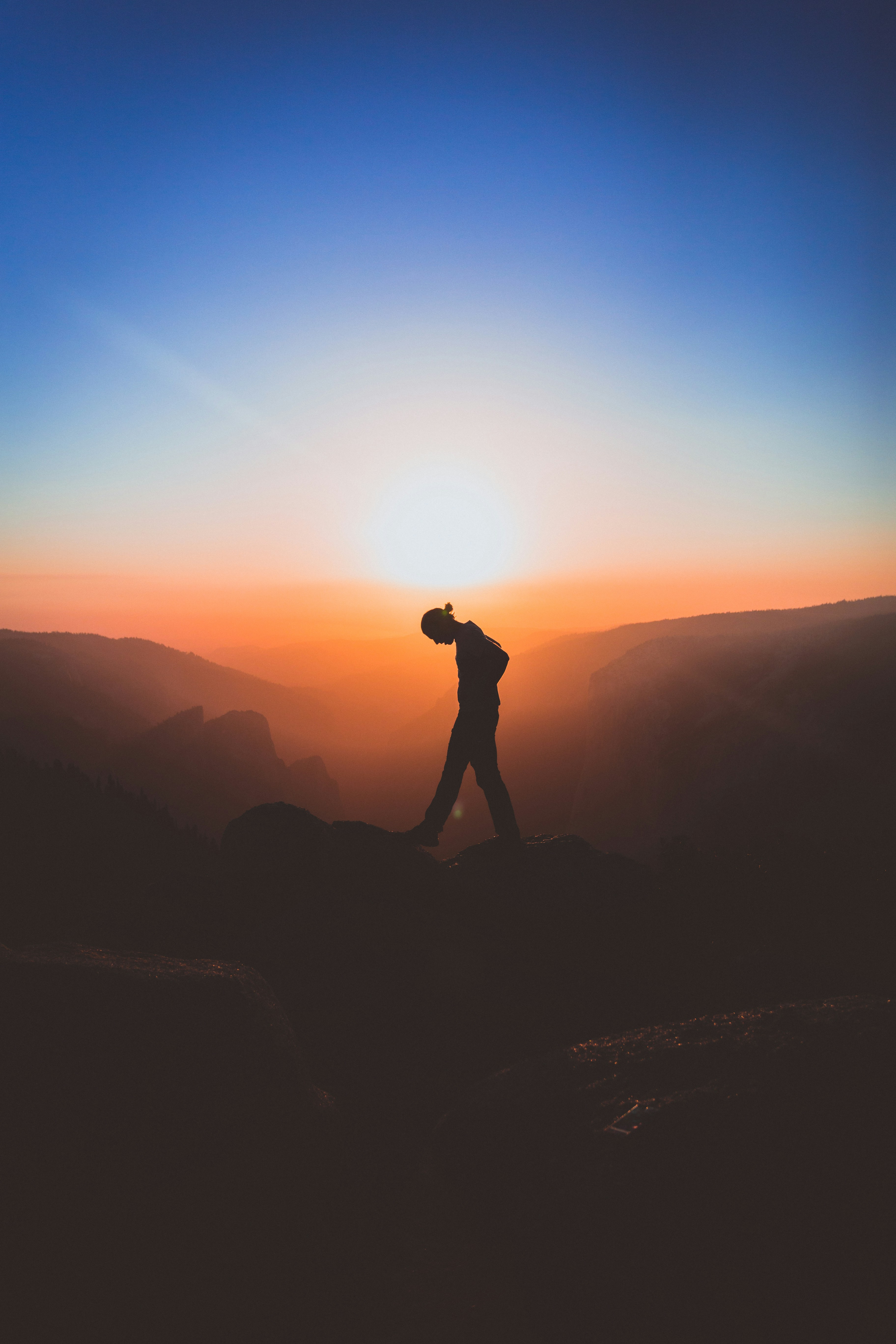 silhouette of man standing on mountain peak photo Free Sunset Image