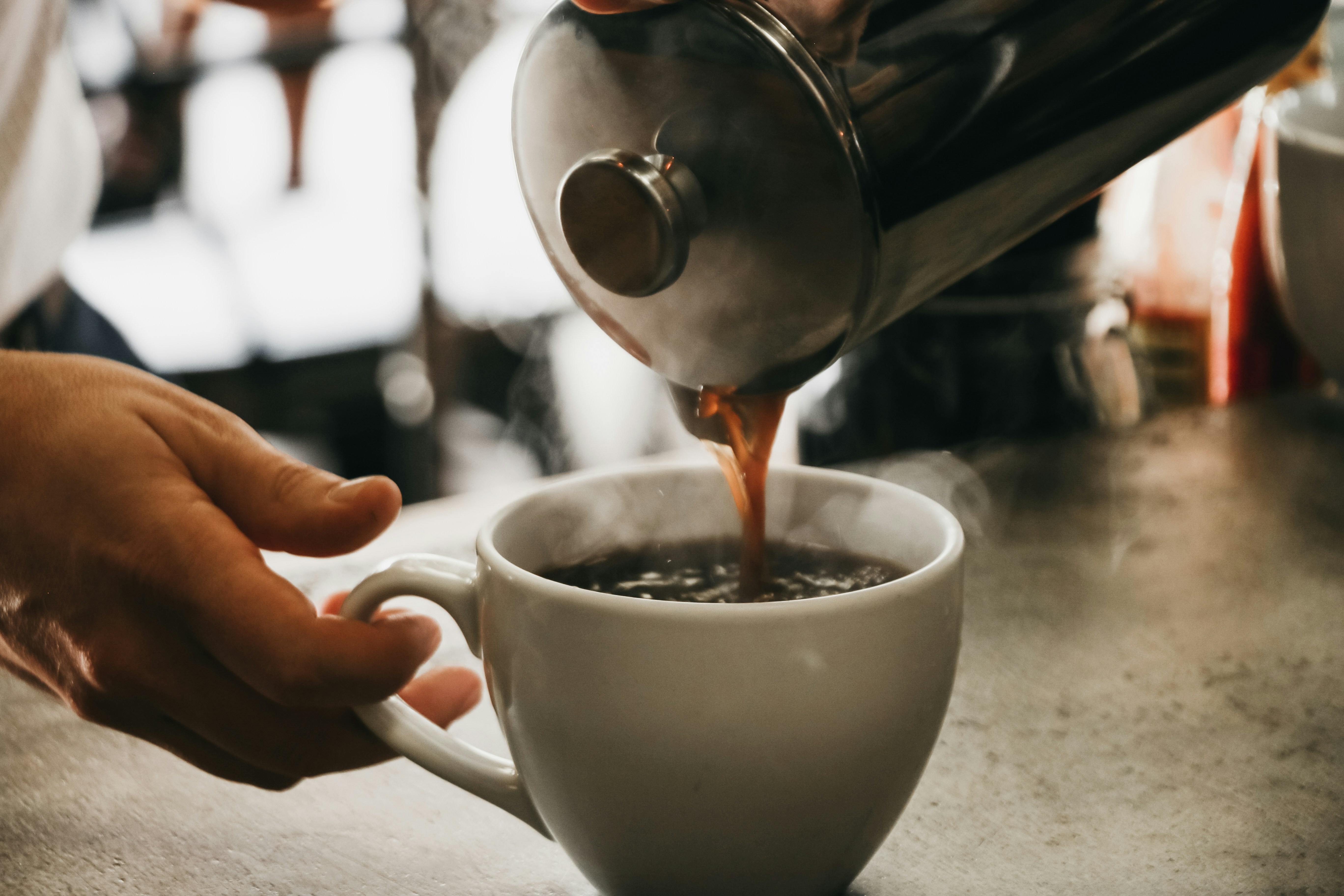 Foto de persona sirviendo café en una taza de cerámica blanca Imagen