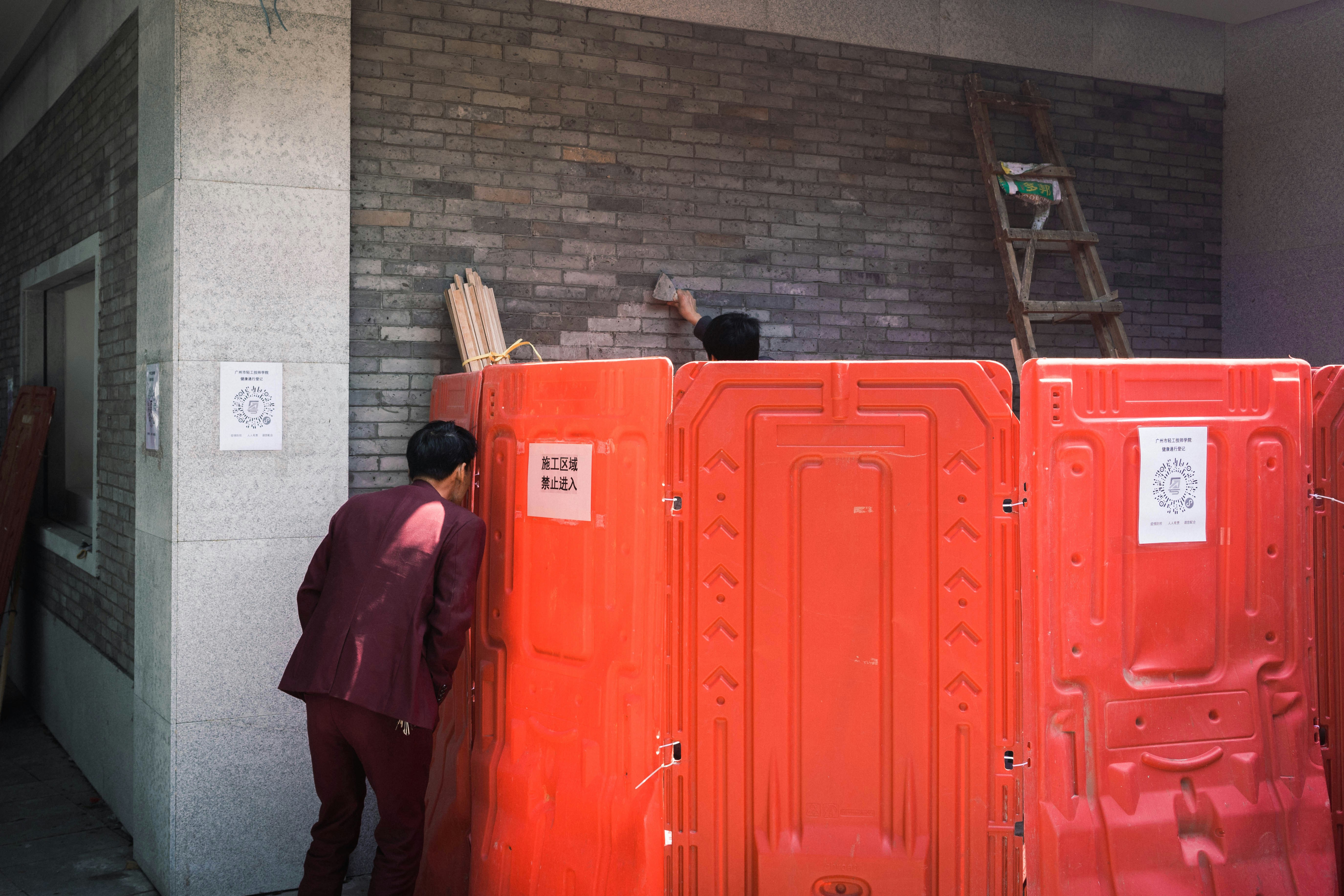A man standing next to a row of orange portable toilets photo Free