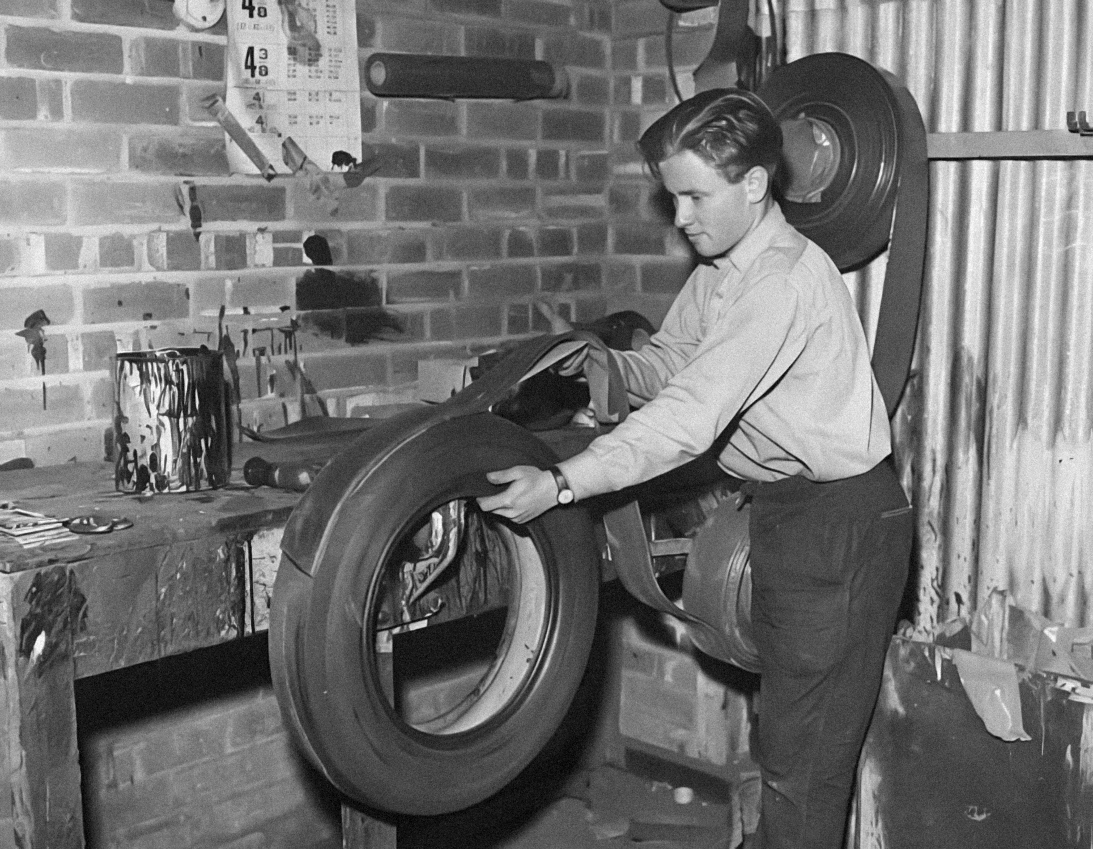 A black and white photo of a man working on a tire photo Free Old