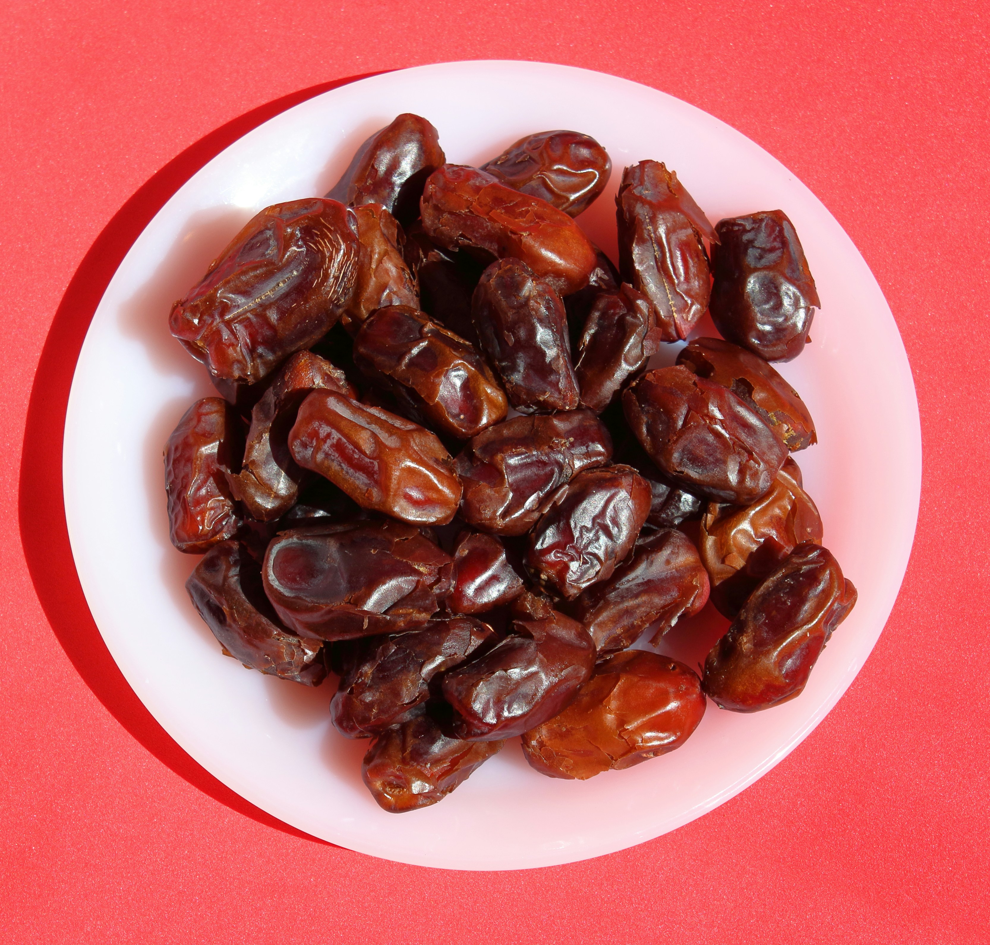 A white plate topped with raisins on a red table photo Free Meyve