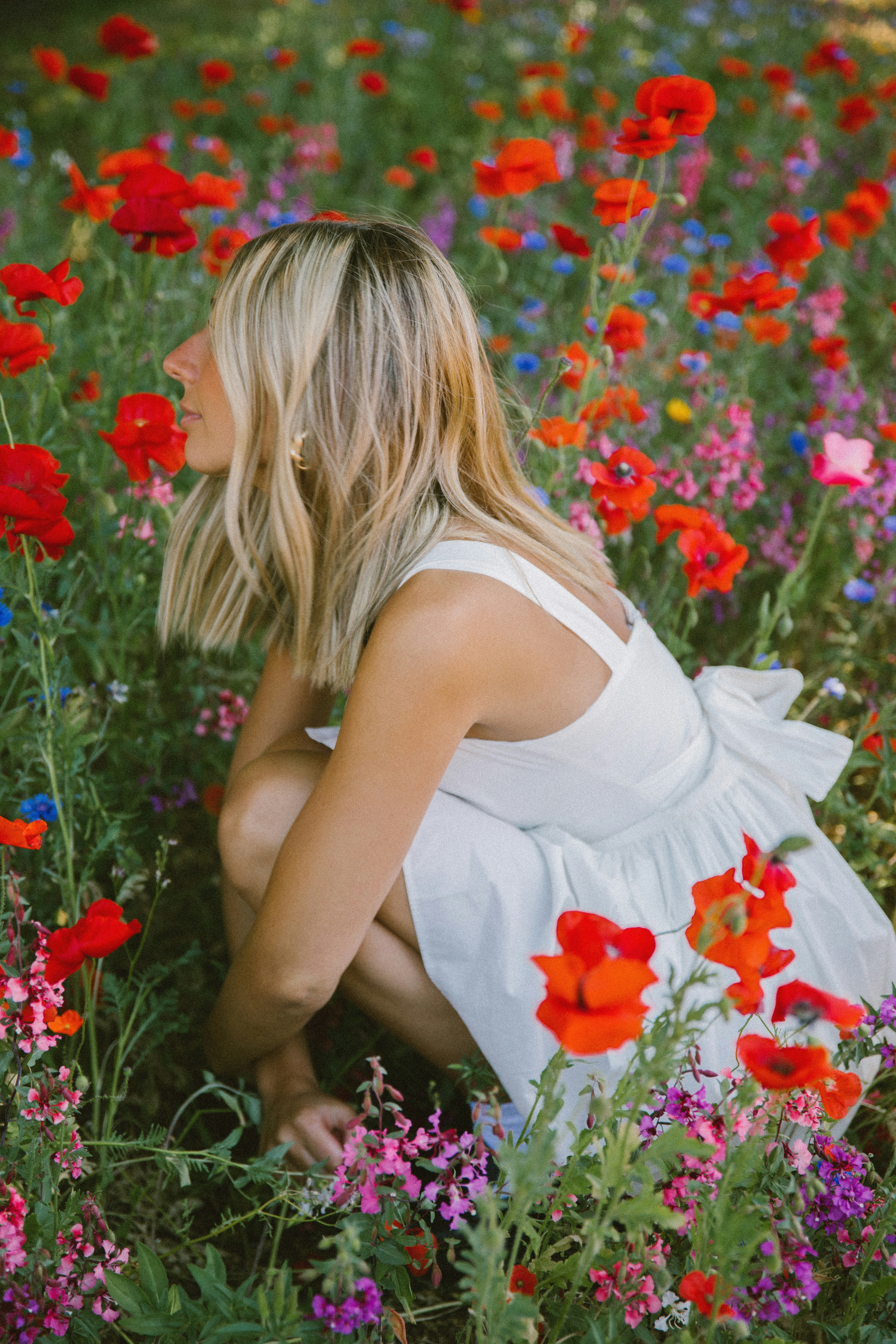 Une femme agenouillée dans un champ de fleurs photo Photo Coquelicots